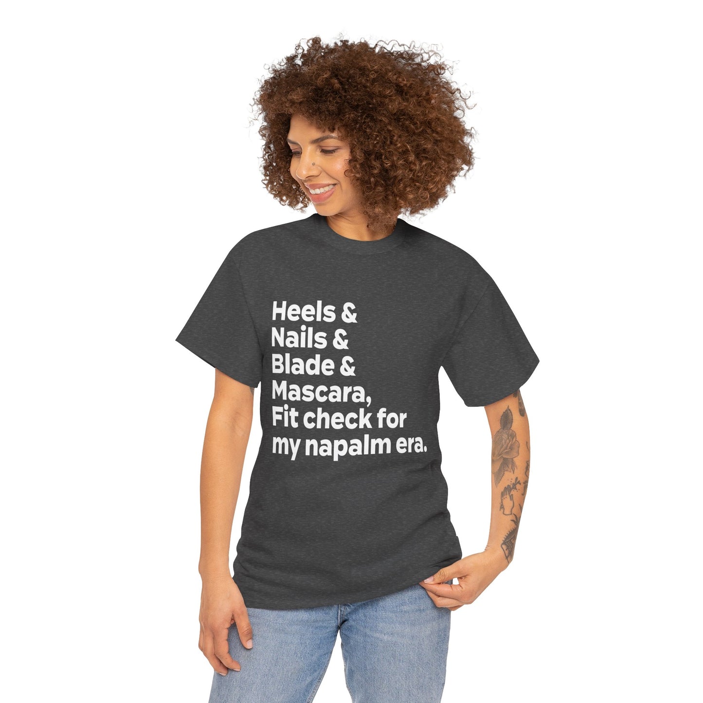 A KPOP Demon Hunters graphic tee featuring the phrase 'heels & nails & blade & mascara, fit check for my napalm era' in bold white lettering.
