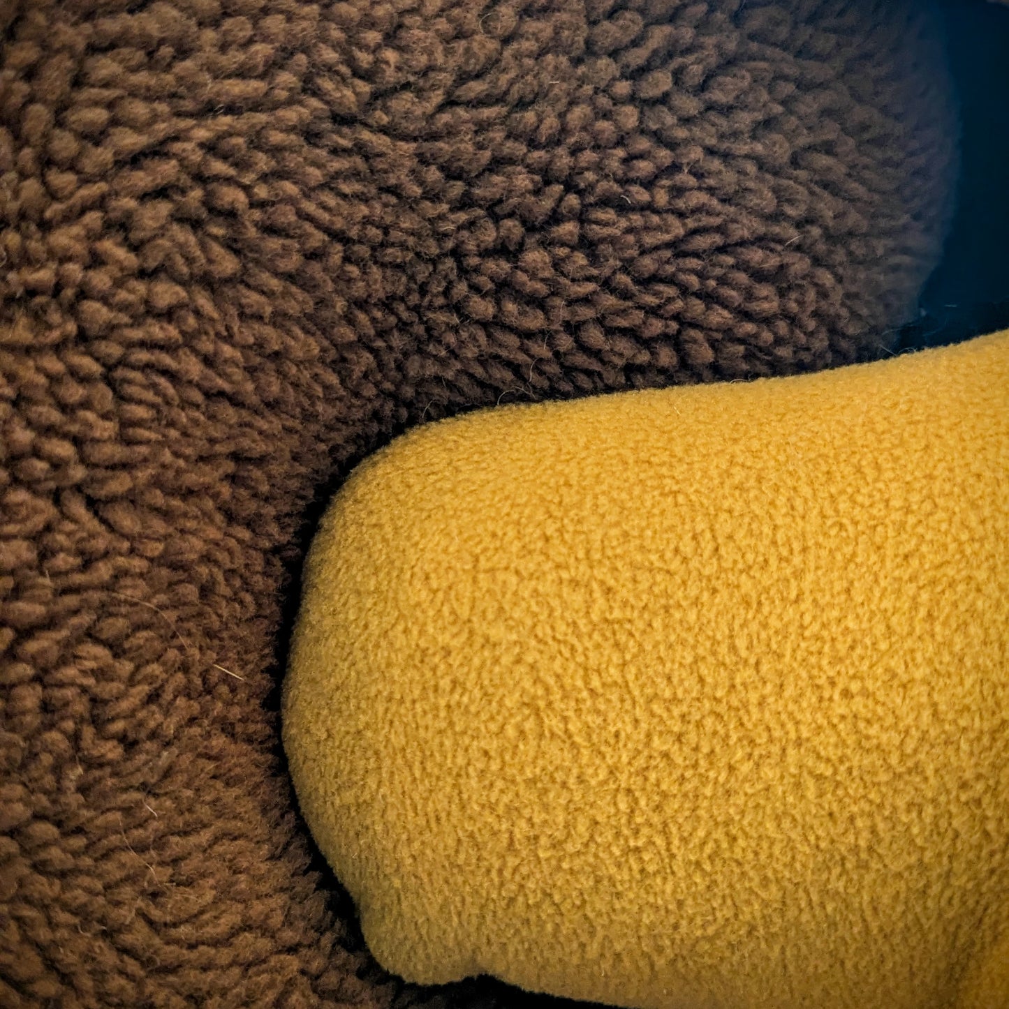 Side by side comparison of medium brown sherpa fabric and golden brown fleece fabric.
