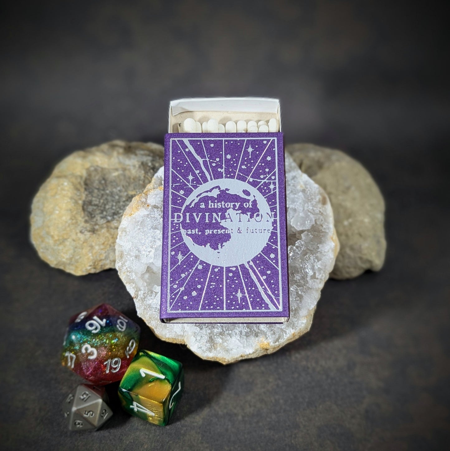 "A History of Divination matchbox by Cantrip Candles, featuring celestial design and RPG dice, ideal for fantasy enthusiasts and tabletop gamers looking to add a mystical, divination-themed accessory."