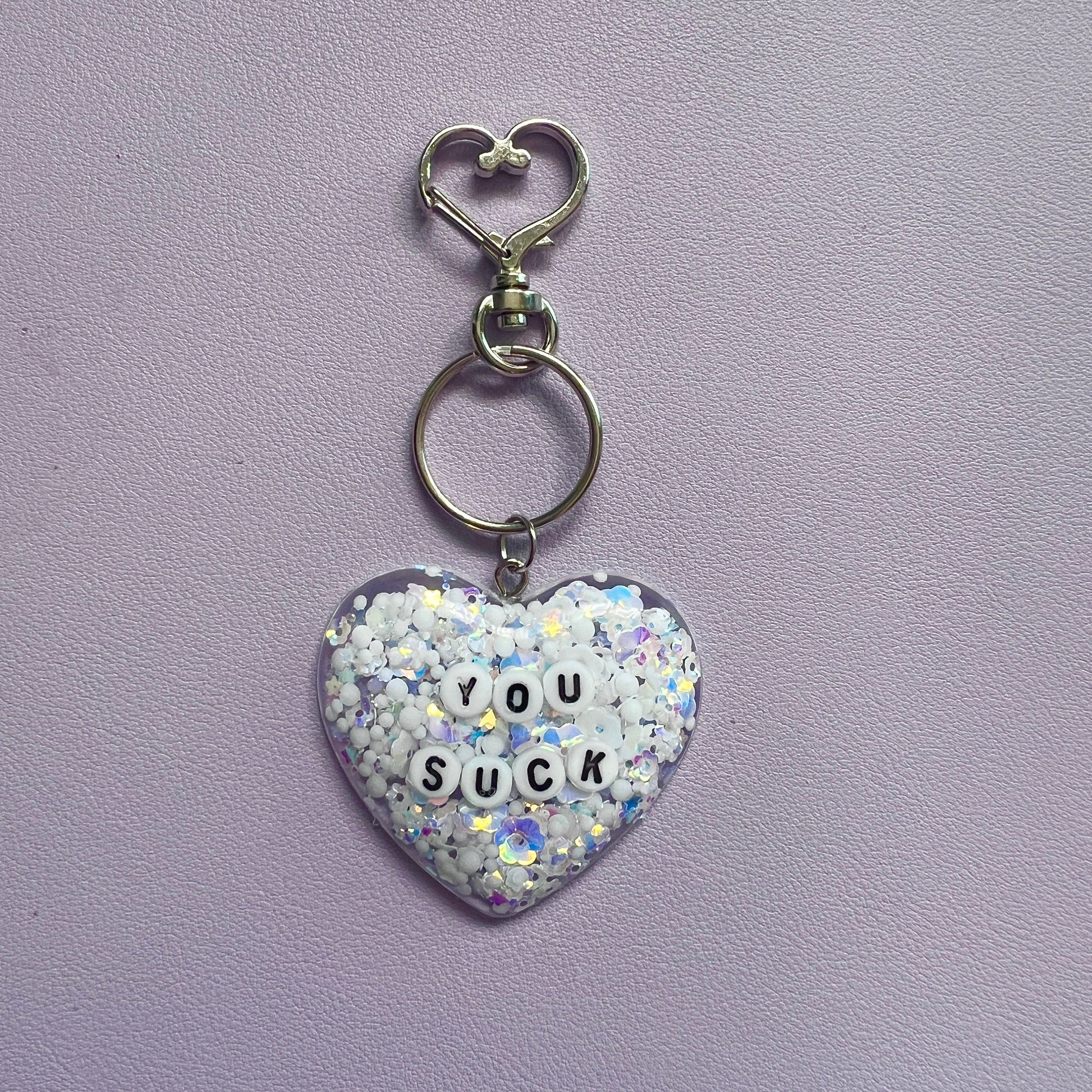 Customizable resin heart keychain with funny phrases. A fun, quirky gift for friends, this keychain can be personalized from a list of fun phrases. Perfect for adding personality to your keys or bags.