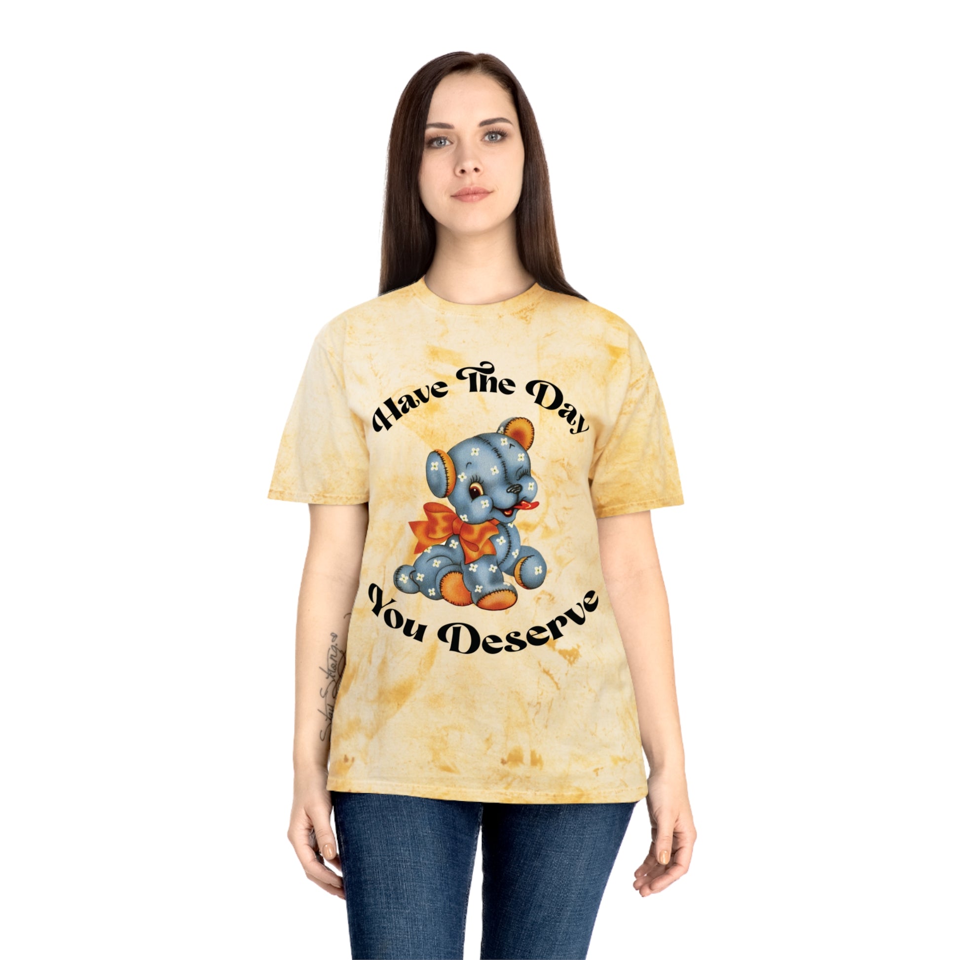 T-shirt with a cute plush bear design in shades of blue, wearing a red bow, accompanied by the playful phrase, Have the Day You Deserve. Casual and relaxed fit for an effortlessly cool look. Available in Blue, Gray, and Citrine.