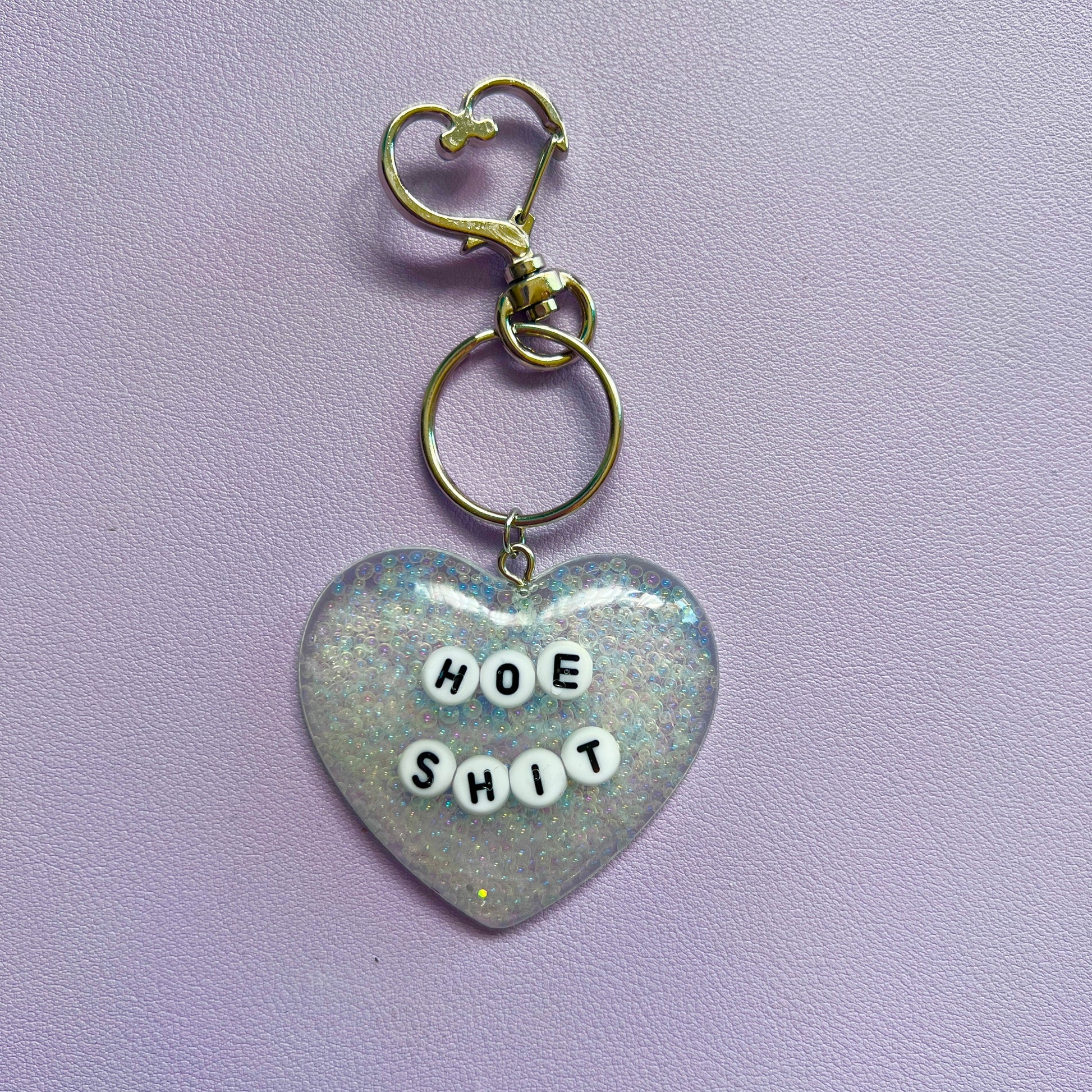 Customizable resin heart keychain with funny phrases. A fun, quirky gift for friends, this keychain can be personalized from a list of fun phrases. Perfect for adding personality to your keys or bags.