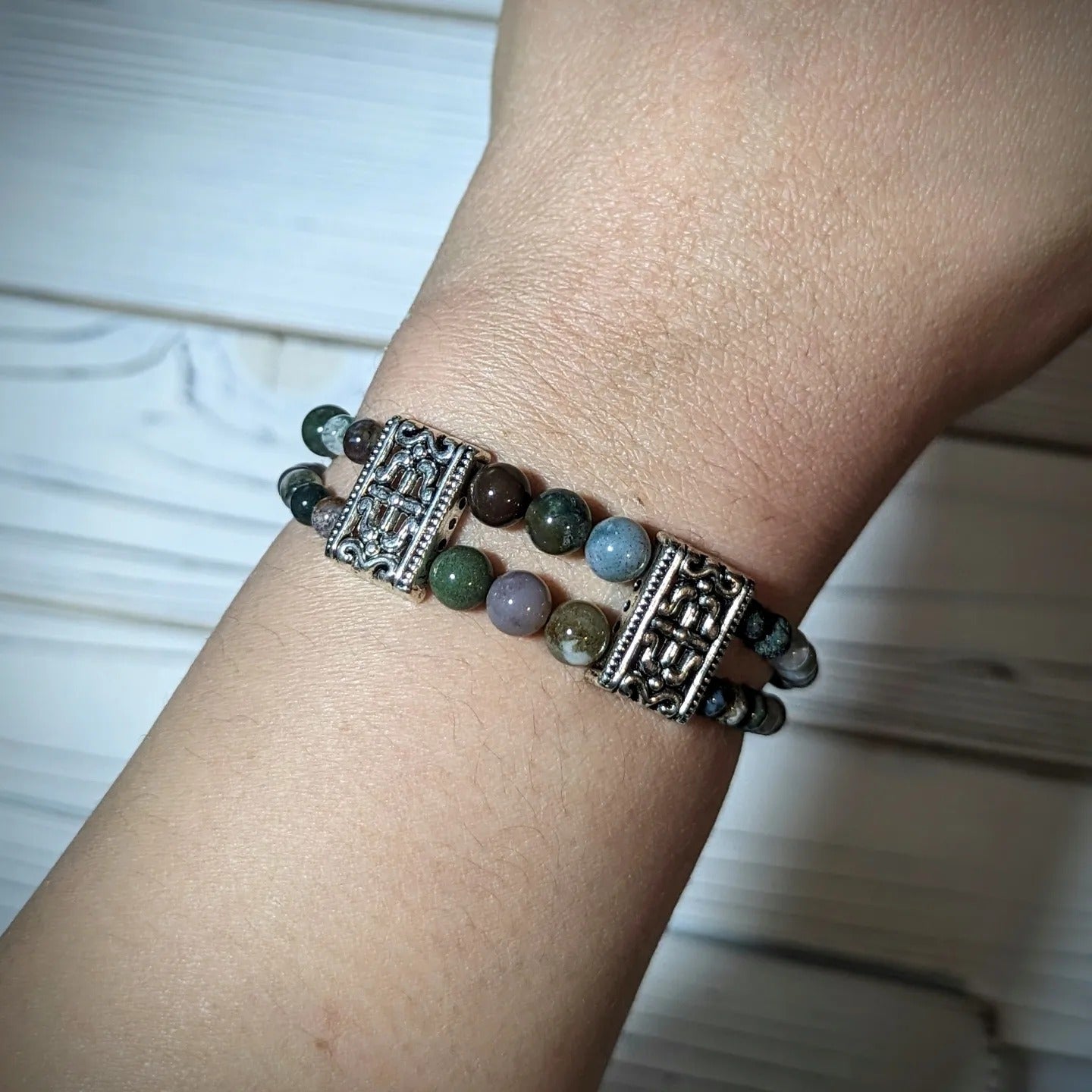 "Elegant double-strand agate bracelet with ornate silver accents, worn on the wrist. Features earthy green, brown, and pink gemstones, perfect for adding a touch of sophistication and natural charm to any outfit."