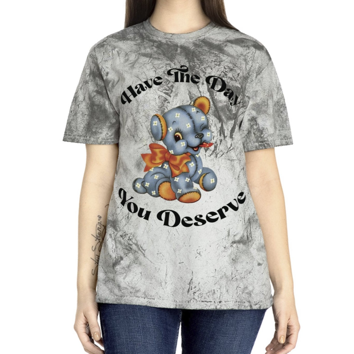 T-shirt with a cute plush bear design in shades of blue, wearing a red bow, accompanied by the playful phrase, Have the Day You Deserve. Casual and relaxed fit for an effortlessly cool look. Available in Blue, Gray, and Citrine.