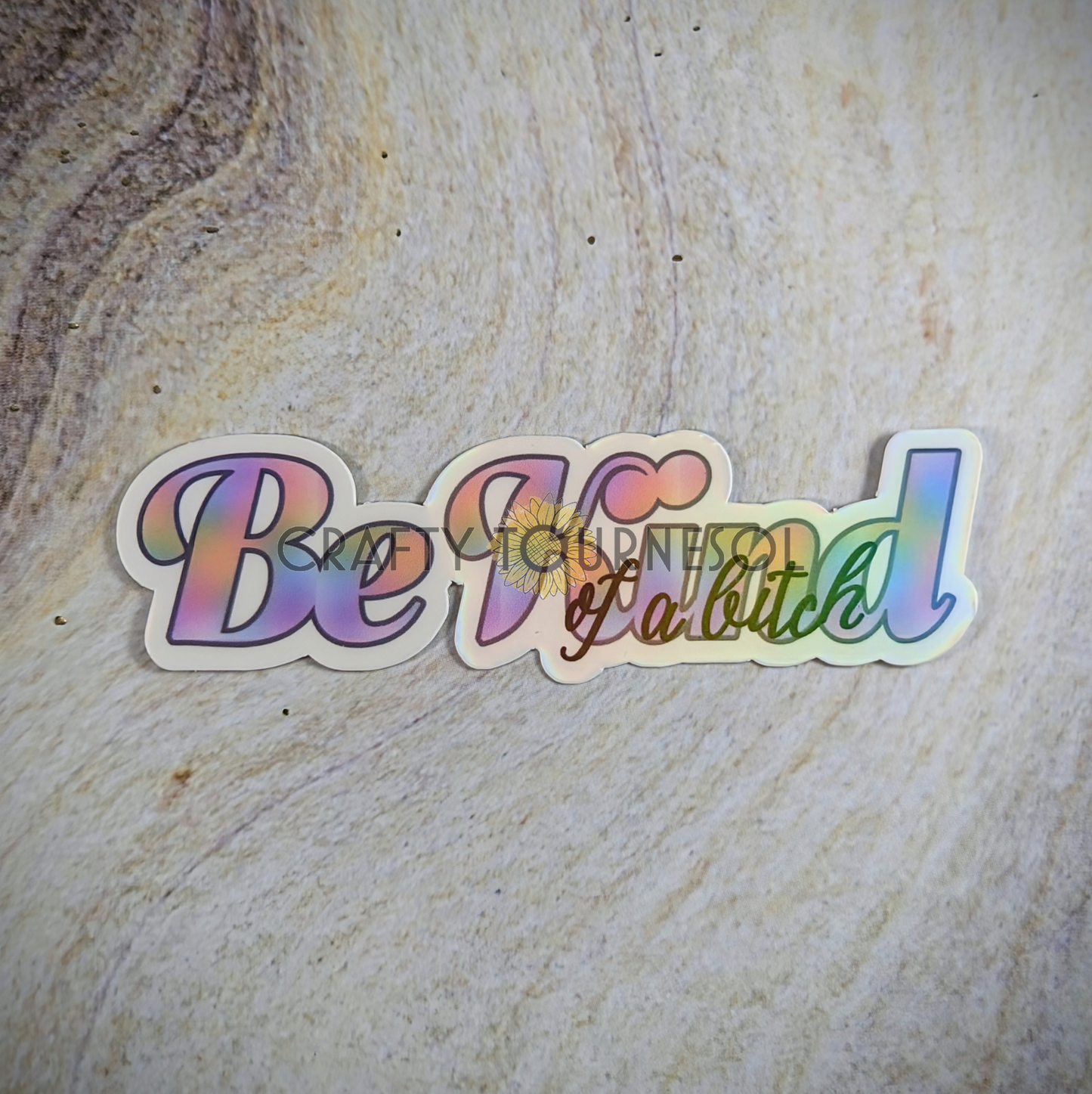 "Be Kind of a Bitch" holographic sticker with bold rainbow text, perfect for empowering vibes and showcasing personality. Set on a textured background, this vibrant design is edgy and inspiring.