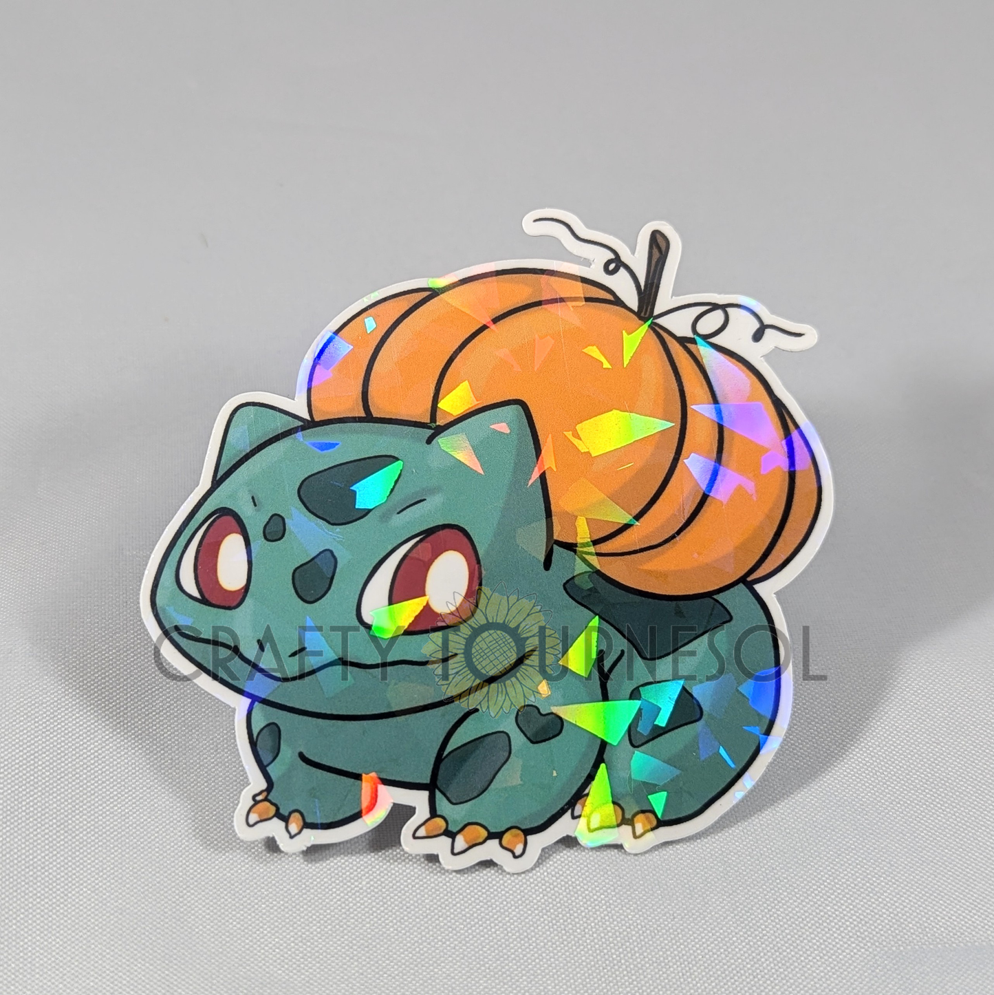 "Holographic Bulbasaur sticker with a Halloween twist, featuring a vibrant orange pumpkin on its back. Perfect for Pokemon fans, this cute sticker adds festive sparkle to any collection or decor."