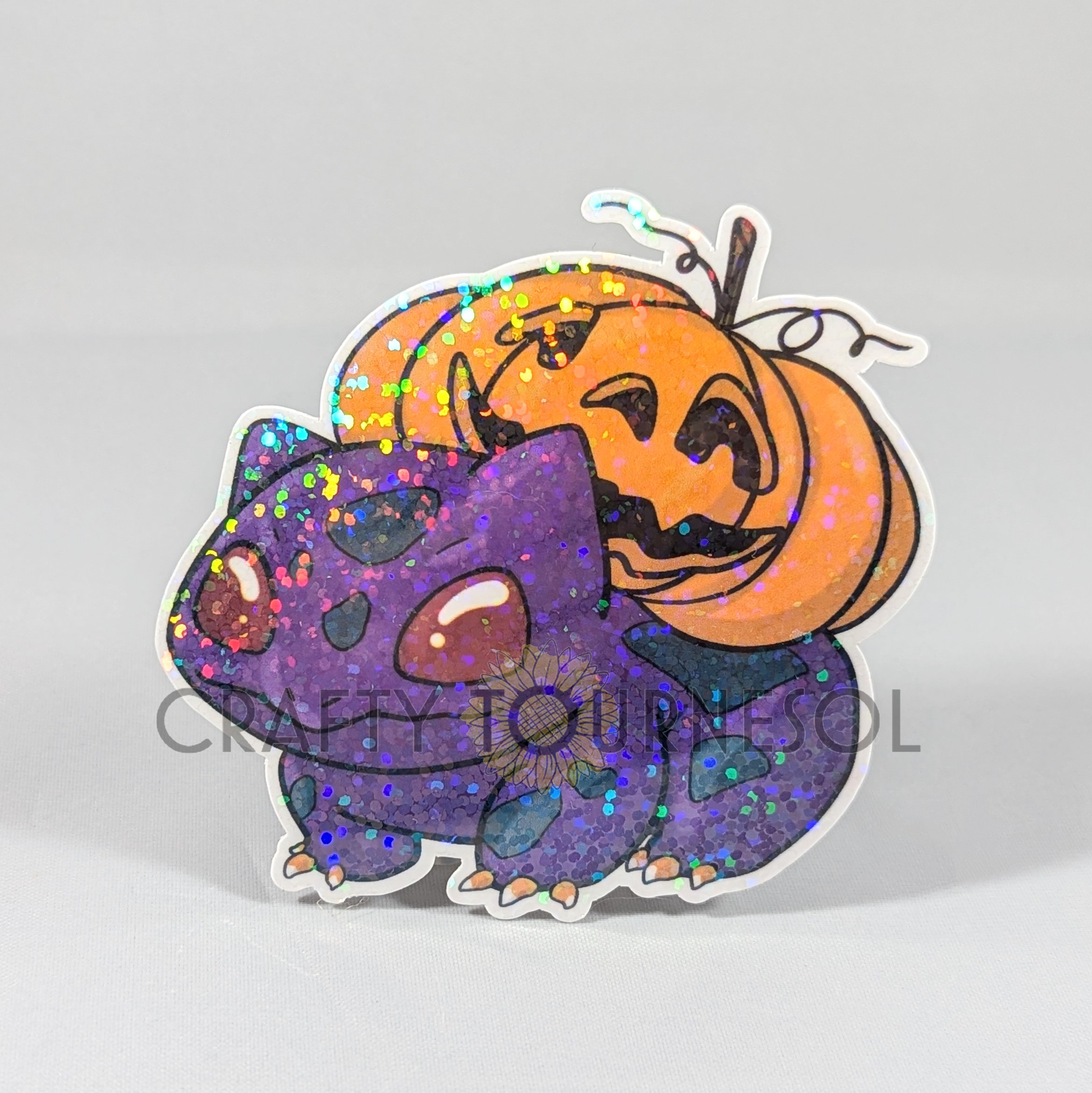 "Holographic purple Bulbasaur sticker with a spooky Halloween theme, featuring a jack-o'-lantern pumpkin on its back. A perfect, festive collectible for Pokemon fans looking to add sparkle to their decor."