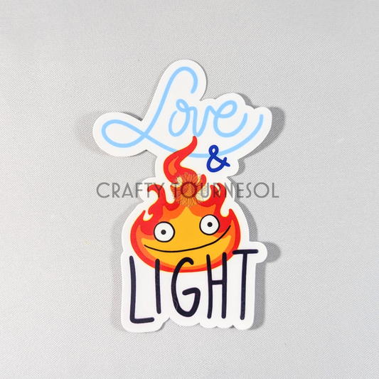 "Sticker featuring a smiling flame character similar to Calcifer with the phrase 'Love & Light' in playful text. Perfect for fans of whimsical designs, adding warmth and positivity to laptops, water bottles, or decor."