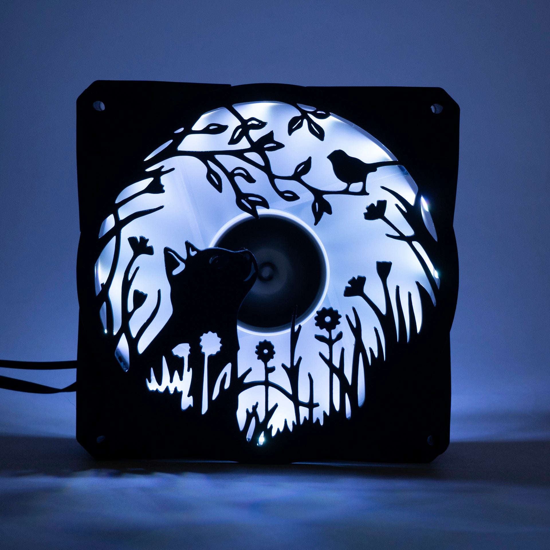 Adorable 3D printed PC fan grill featuring a cat and bird in a garden scene. Adds cozy charm and personality to any gaming or desktop setup.