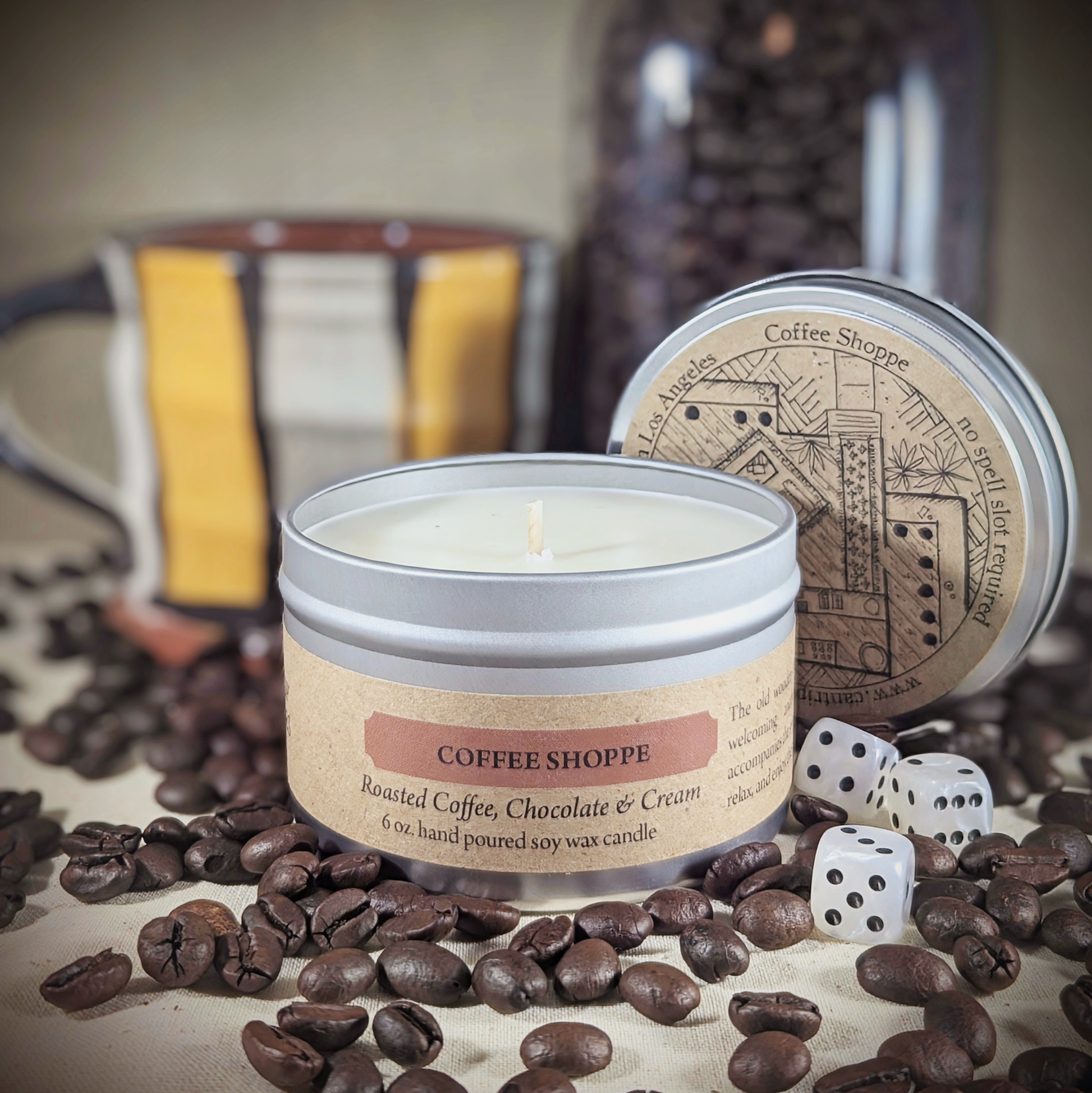 "Coffee Shoppe 6 oz soy wax candle tin by Cantrip Candles, featuring Roasted Coffee, Chocolate & Cream scents, staged with RPG dice and coffee beans, perfect for creating a cozy, café-inspired ambiance for gamers and coffee lovers."