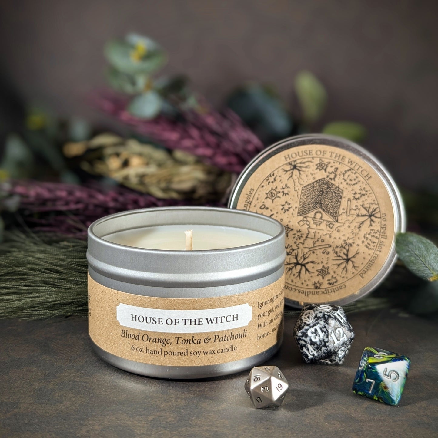 Alt text: "House of the Witch 6 oz soy wax candle tin in Blood Orange, Tonka & Patchouli scent with RPG dice and nature-inspired decor. Perfect for enhancing ambiance during gaming sessions or creating a mystical home vibe."