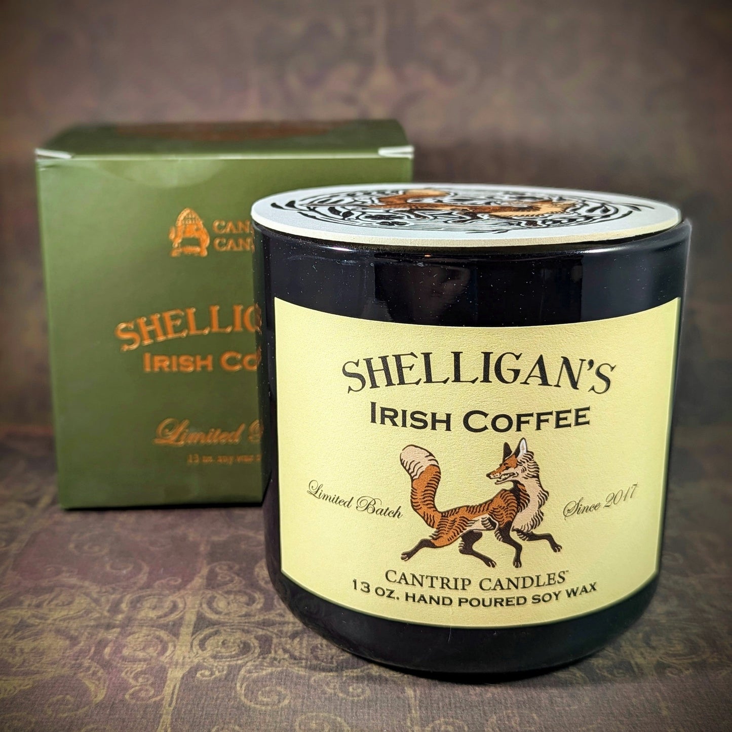 
"Shelligan's Irish Coffee candle by Cantrip Candles, 13 oz soy wax, limited batch. Hand-poured with rich Irish coffee scent. Shown with green packaging and fox illustration, perfect for cozy atmospheres."