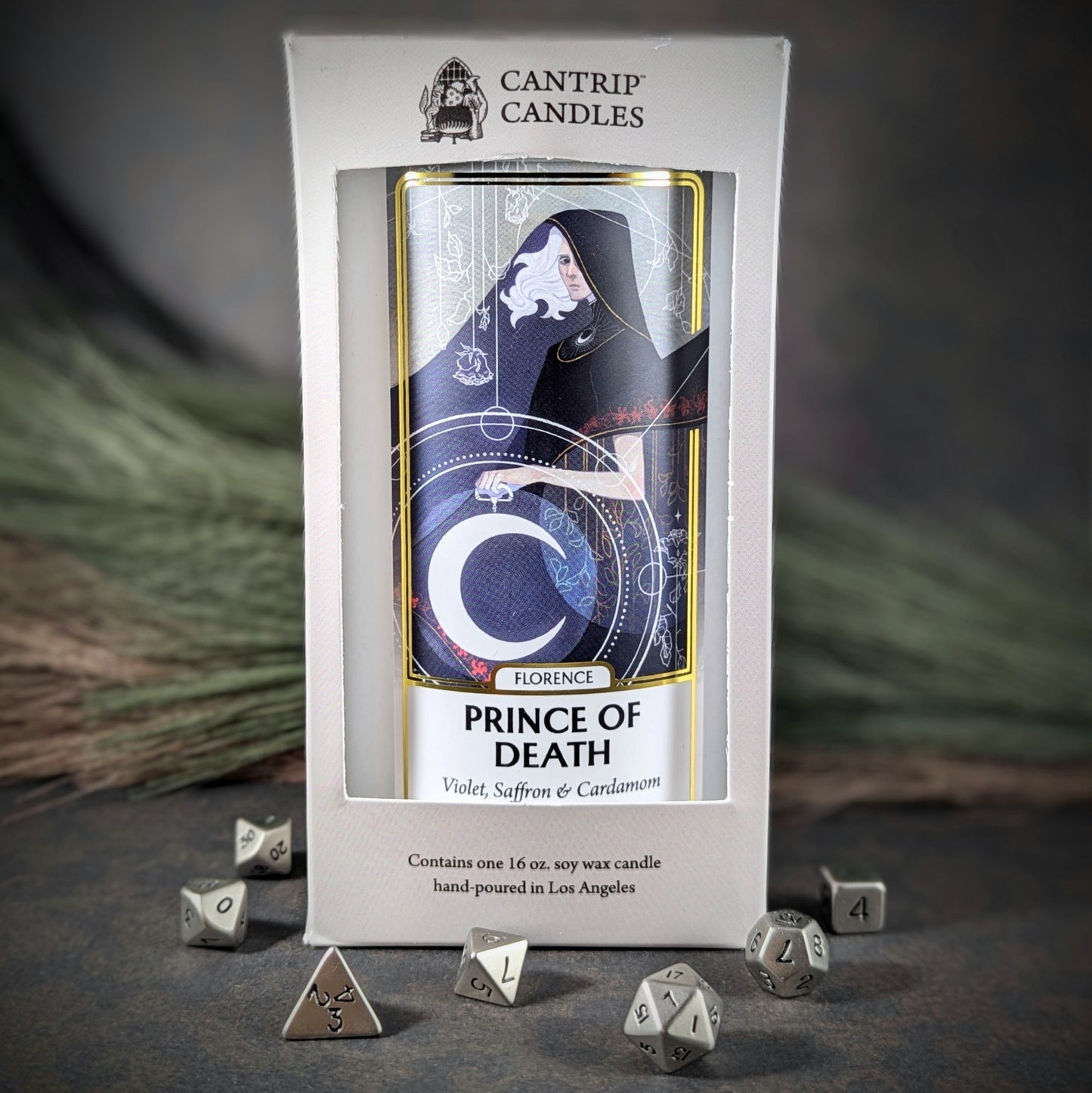 "Florence, Prince of Death 16 oz soy wax candle by Cantrip Candles featuring violet, saffron, and cardamom scent, with mystical artwork of a cloaked figure, staged with RPG dice, ideal for creating an ethereal, gothic ambiance in any space."