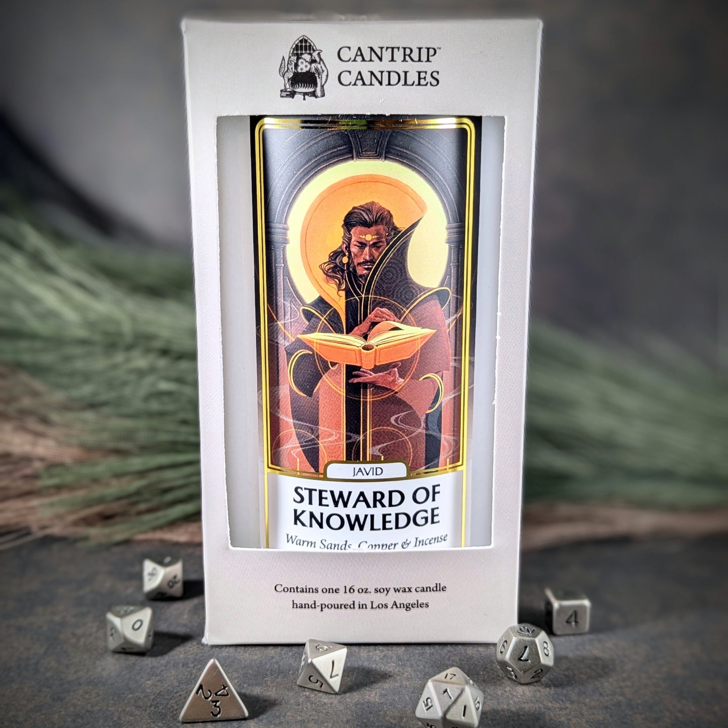 "Javid, Steward of Knowledge 16 oz soy wax candle by Cantrip Candles featuring warm sands, copper, and incense scent, with artwork of a wise figure holding a book, staged with RPG dice, perfect for creating a scholarly, mystical ambiance."