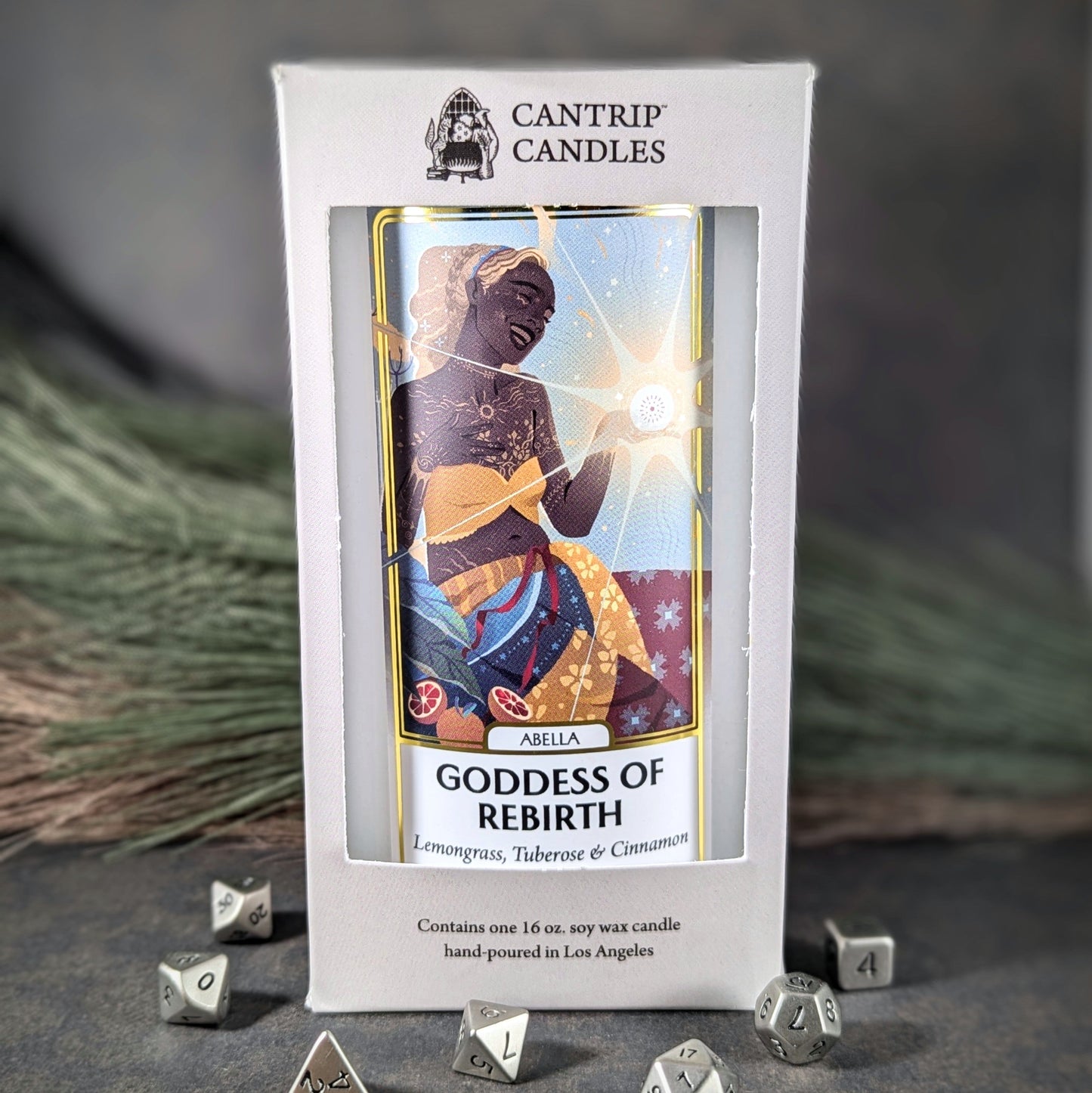 "Abella, Goddess of Rebirth 16 oz soy wax candle by Cantrip Candles featuring lemongrass, tuberose, and cinnamon scent, with vibrant artwork of a goddess, staged with RPG dice, ideal for creating a rejuvenating, spiritual ambiance."