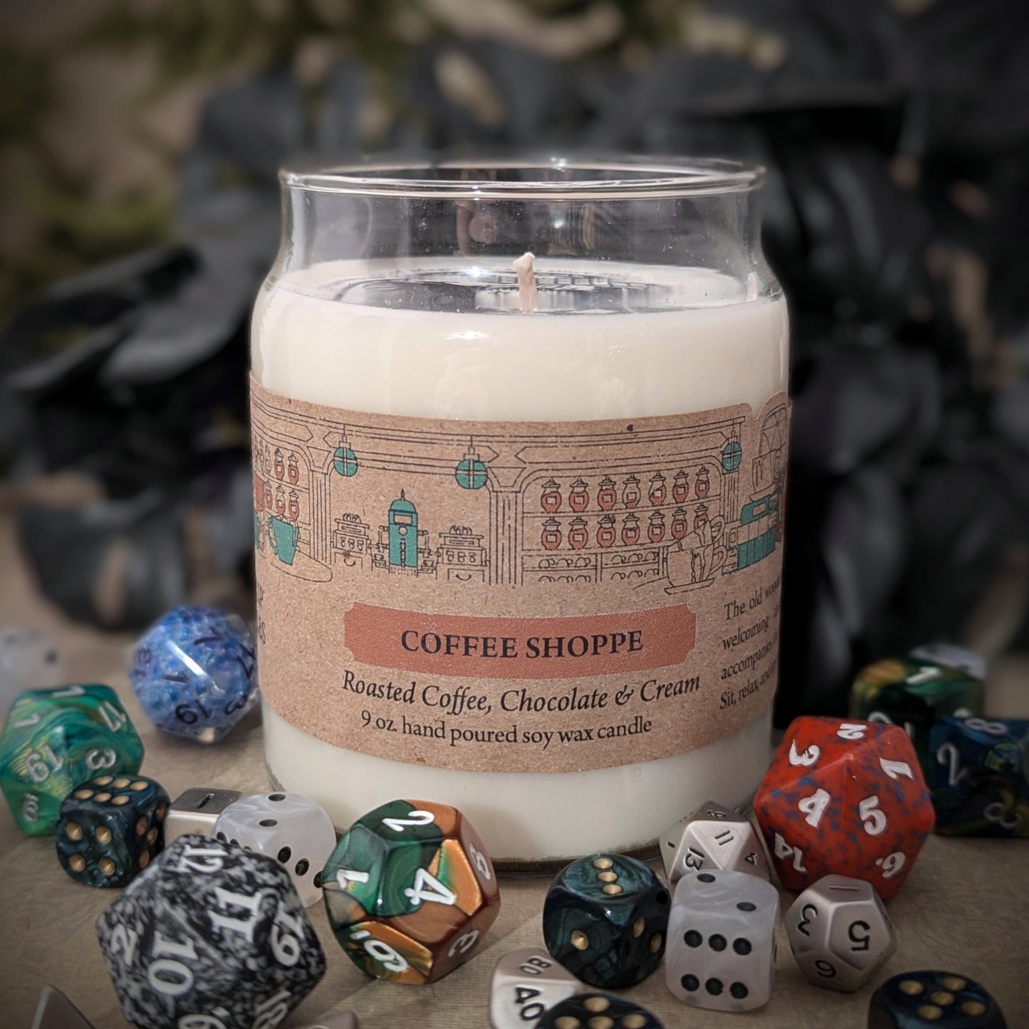 "Coffee Shoppe candle by Cantrip Candles, 9 oz soy wax with rich scents of roasted coffee, chocolate, and cream. Staged with RPG dice. Perfect for cozy ambiance or themed tabletop gaming sessions."