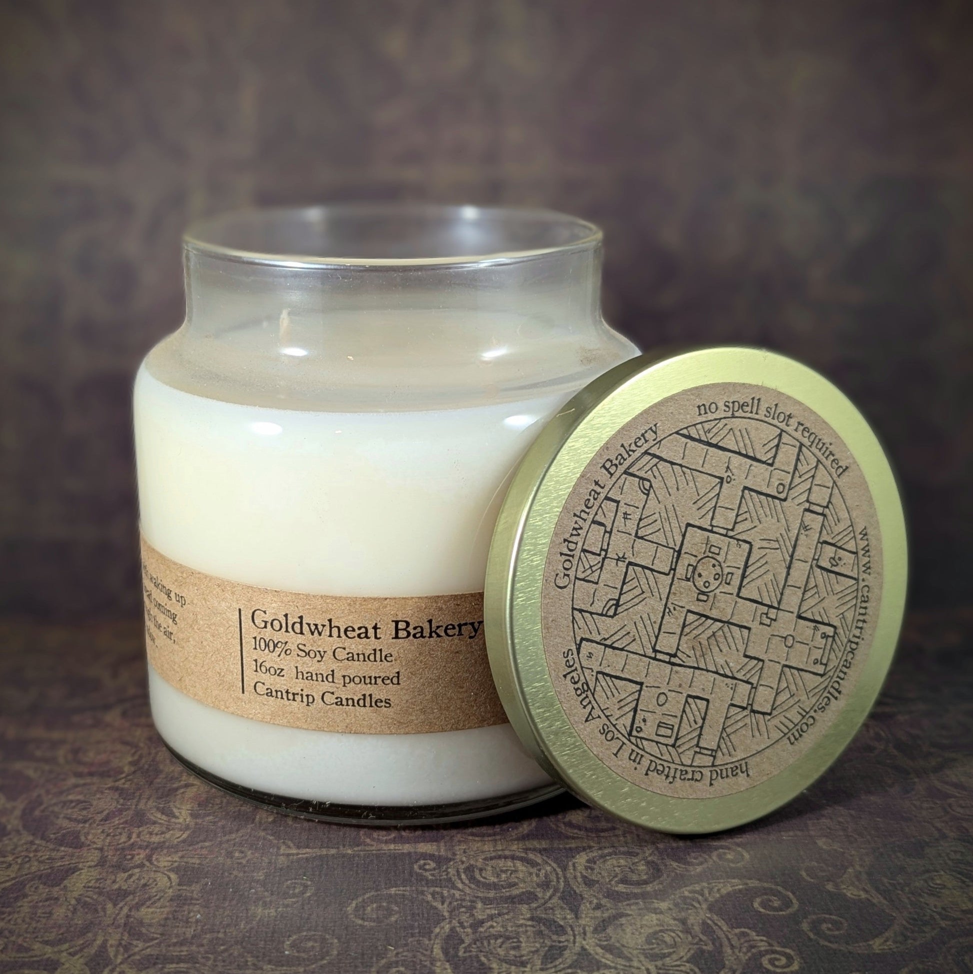 "Goldwheat Bakery candle by Cantrip Candles, 16 oz hand-poured soy wax with a cozy bakery scent. Perfect for creating a warm, inviting atmosphere. Unique D&D-inspired map design lid for fantasy and tabletop fans."