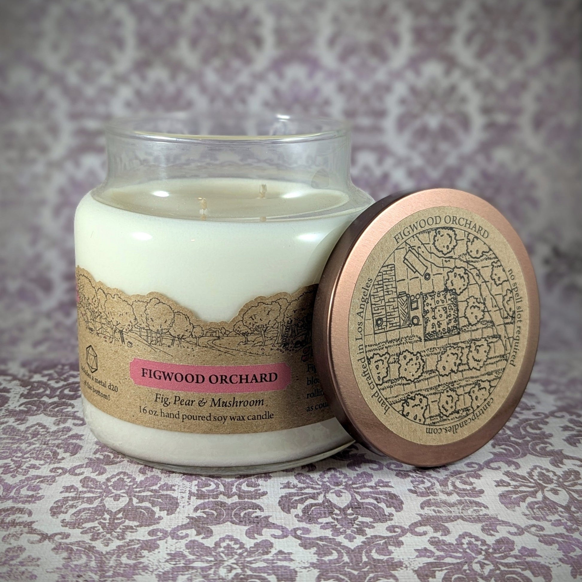 "Figwood Orchard candle by Cantrip Candles, 16 oz soy wax, featuring a unique fig, pear, and mushroom scent. Hand-poured with orchard scene label and decorative lid, perfect for a cozy, nature-inspired ambiance."