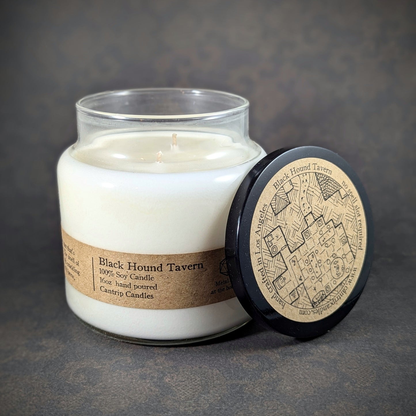 "Black Hound Tavern candle by Cantrip Candles, 16 oz soy wax blend with whiskey and firewood scent profile. Ideal for RPG and fantasy lovers seeking ambiance with custom tavern map lid. Hand-poured, immersive tabletop decor."