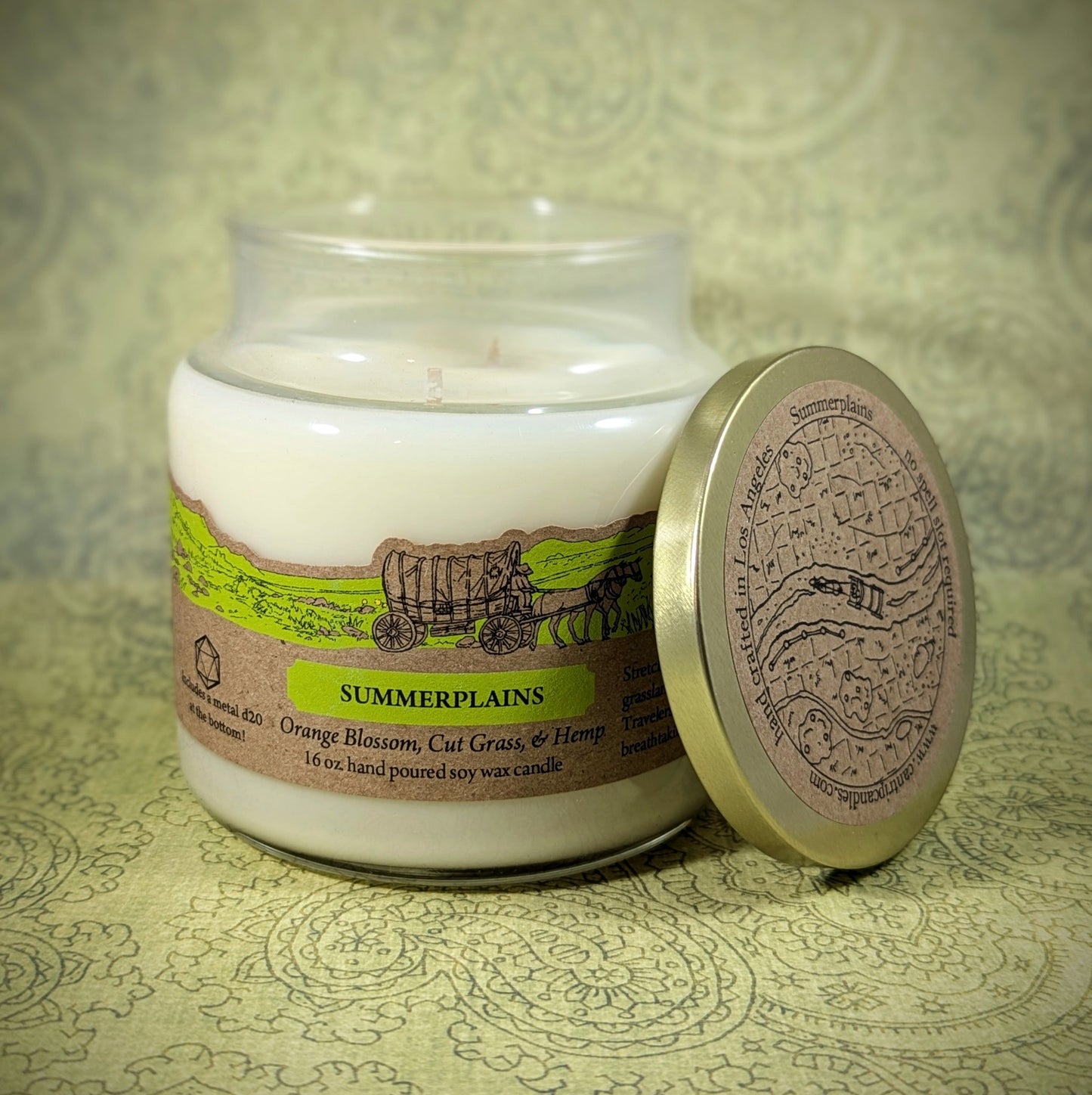 "Summerplains candle by Cantrip Candles, 16 oz soy wax with scents of orange blossom, cut grass, and hemp. Features rustic artwork and map lid design, evoking open plains and warm summer breezes."