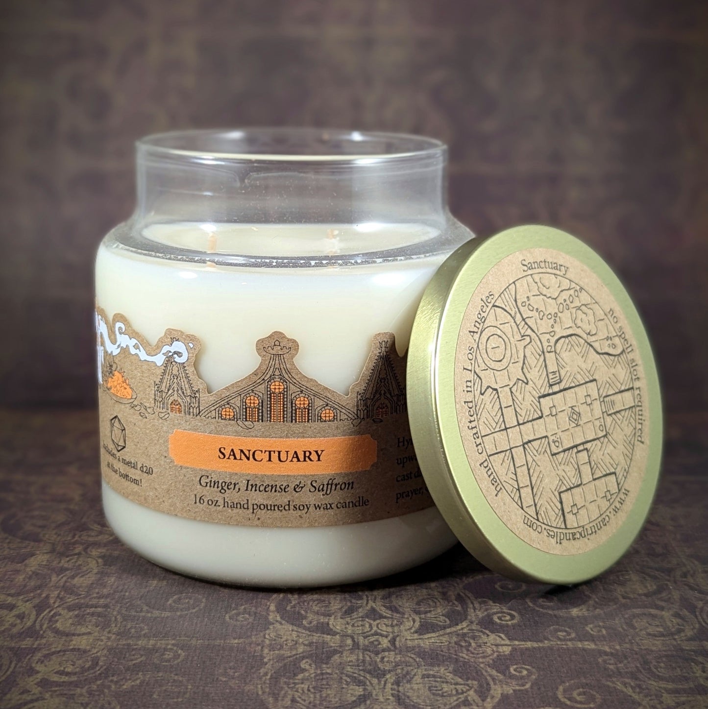 "Sanctuary candle by Cantrip Candles, 16 oz hand-poured soy wax with soothing scents of ginger, incense, and saffron. Beautifully crafted with an intricate sanctuary design on lid, ideal for relaxation."