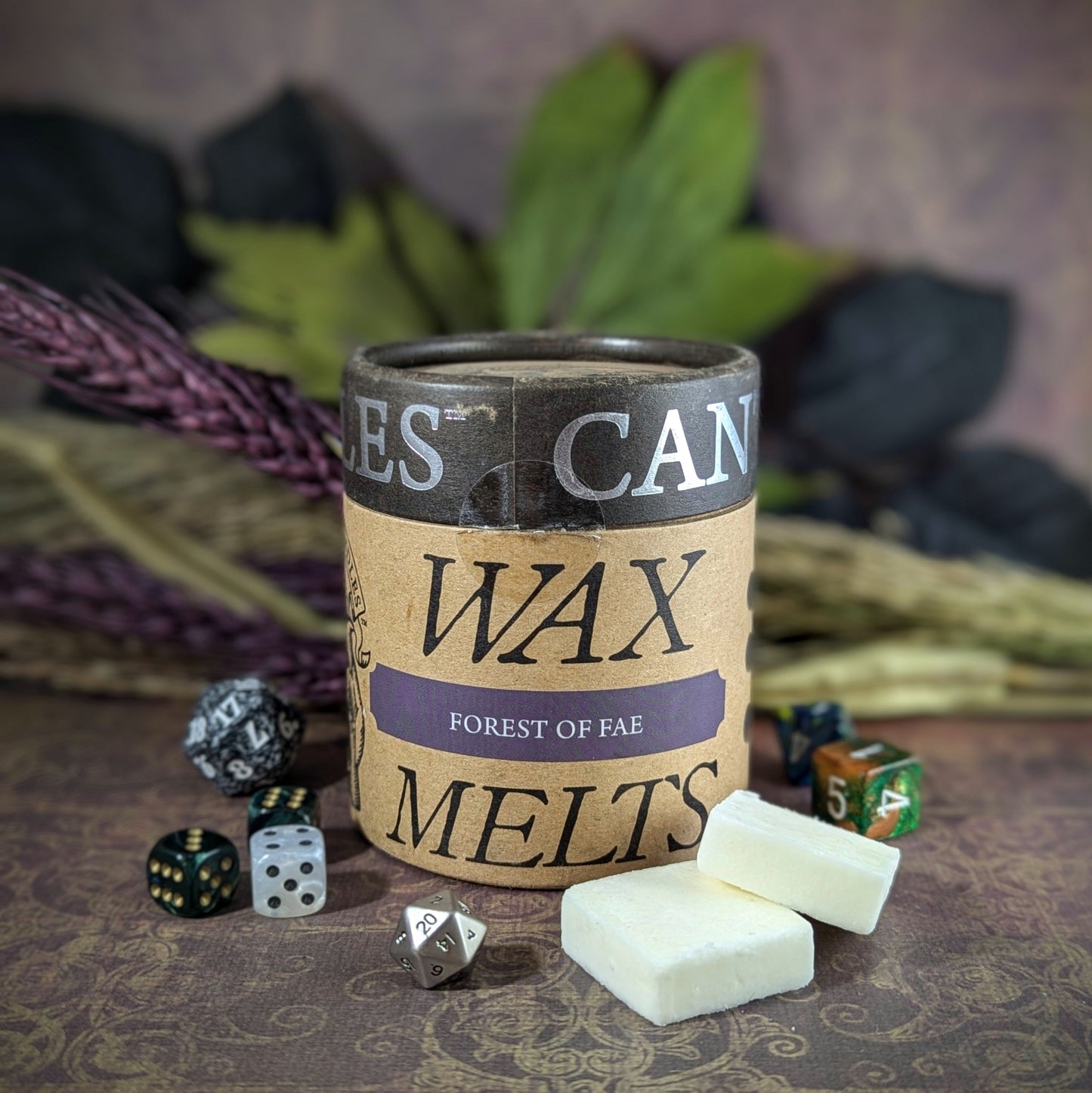 "Cardboard canister of Forest of Fae 5 oz soy wax melts by Cantrip Candles, with enchanting scents of jasmine, neroli, tomato leaf, and amber, staged with florals and RPG dice. Perfect for fantasy lovers."