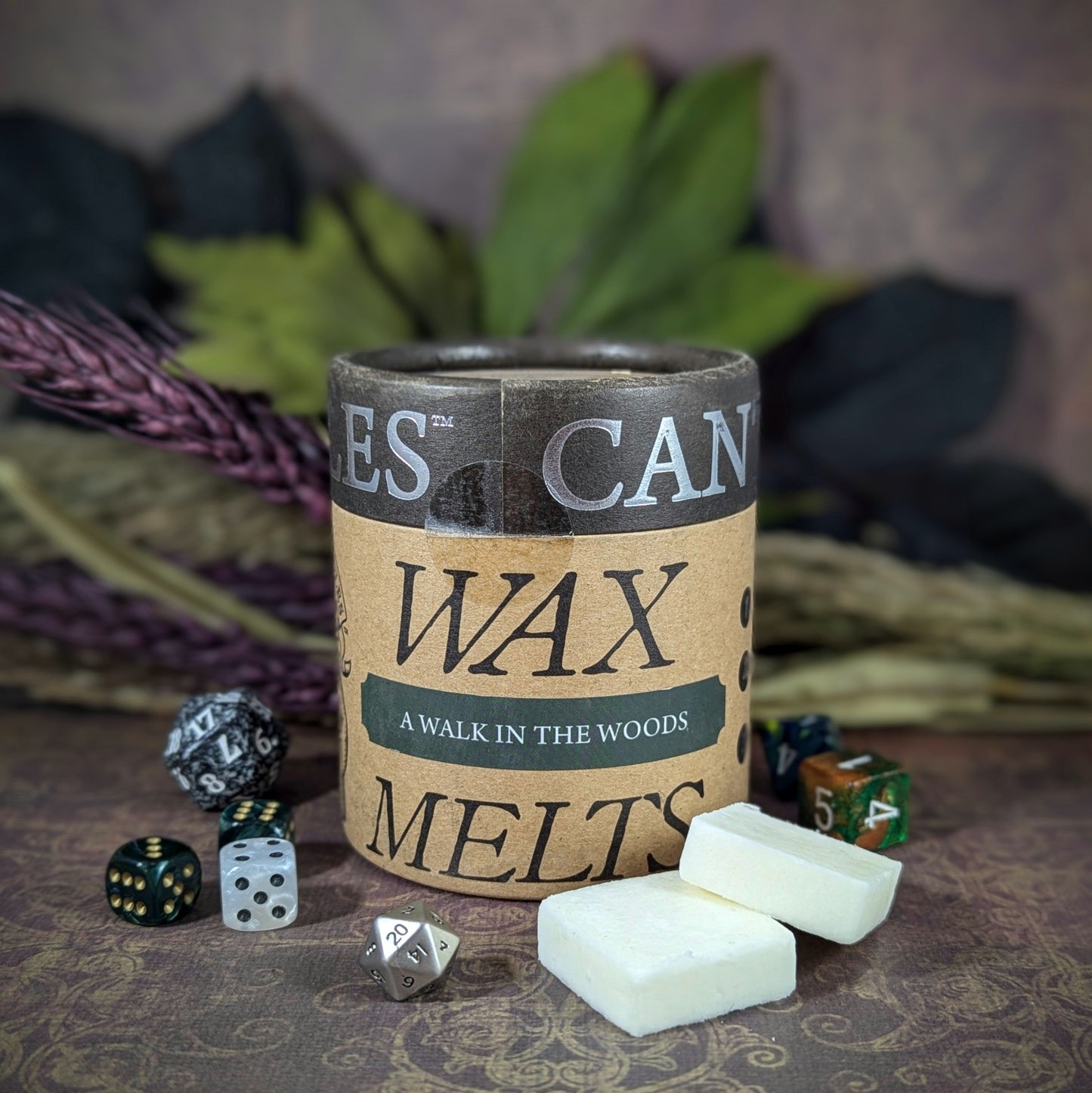 "Cardboard canister of A Walk in the Woods 5 oz soy wax melts by Cantrip Candles, pine and sandalwood scent, staged with florals and RPG dice. Perfect for nature lovers and cozy ambiance seekers."