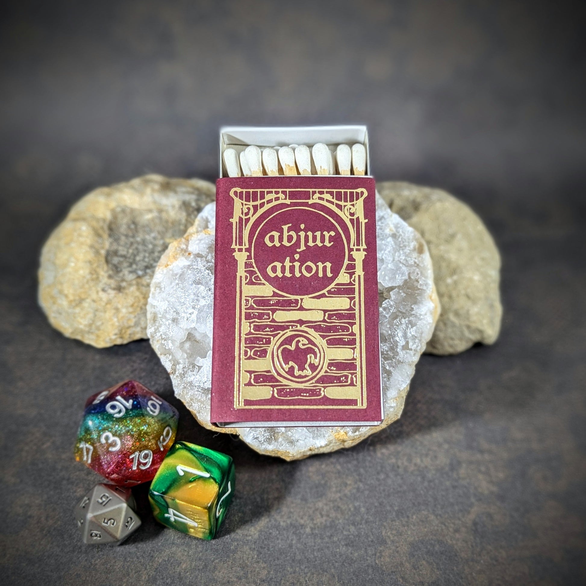 "Abjuration matchbox by Cantrip Candles with RPG dice and stone decor, featuring elegant, fantasy-inspired design, perfect for tabletop gamers and fantasy enthusiasts seeking an enchanting accessory."