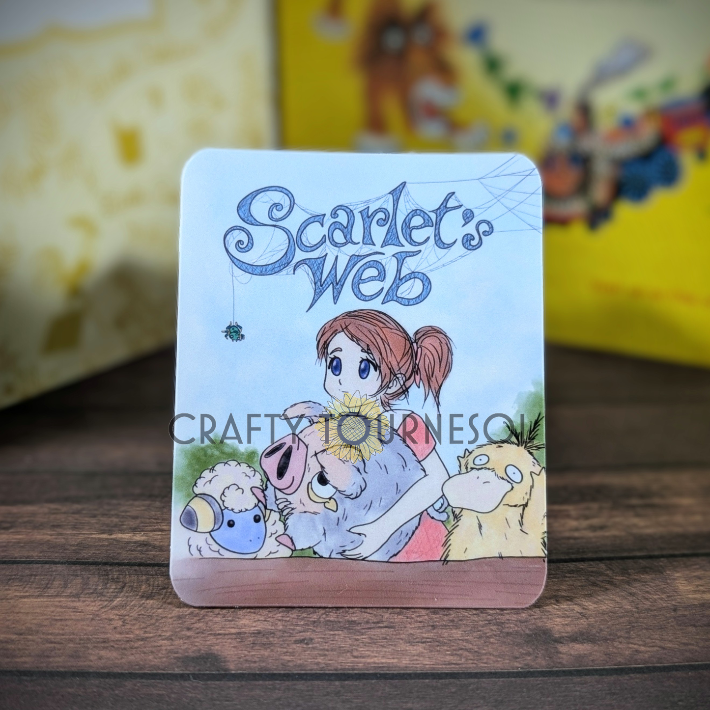 "Vinyl sticker titled Scarlet's Web, with a girl with brown hair holding a LeChonk, surrounded by a Psyduck and Mareep, like the Charlotte's Web storybook cover, blending storybook charm and gaming aesthetics, set against a soft wooden and blurred background."