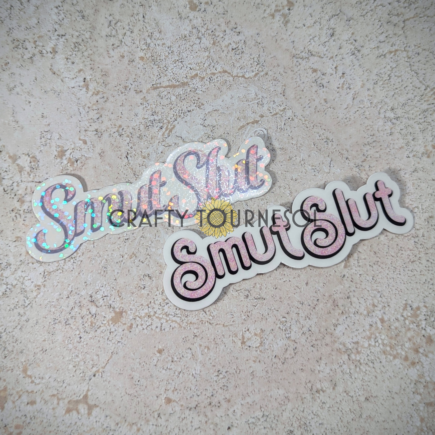 Two "Smut Slut" stickers with two different styles of elegant pink text, perfect for book lovers and spice enthusiasts. Set against a neutral marble background, this design adds a bold, fun flair to your aesthetic.