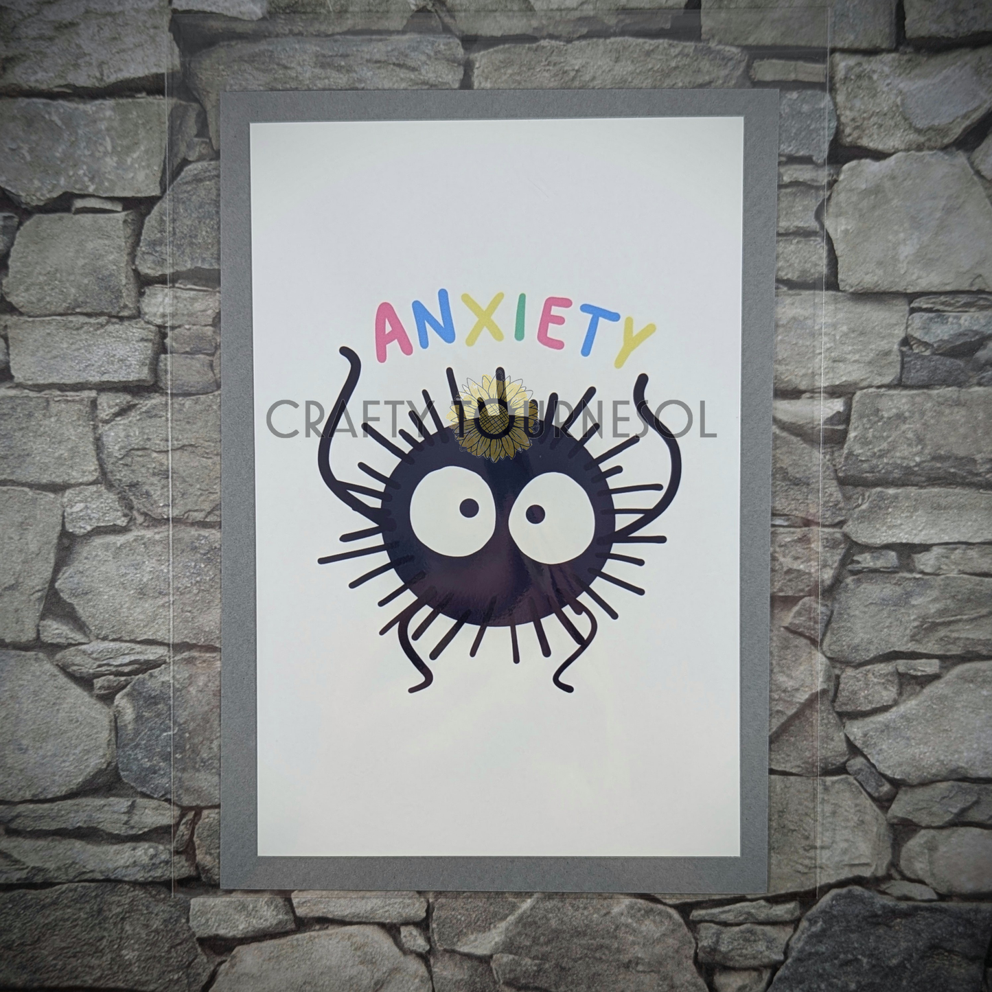 "4"x6" fanart print of soot sprite, holding 'Anxiety' text in playful colors. Perfect for anime fans and mental health advocates adding a playful, geeky touch to favorite space."