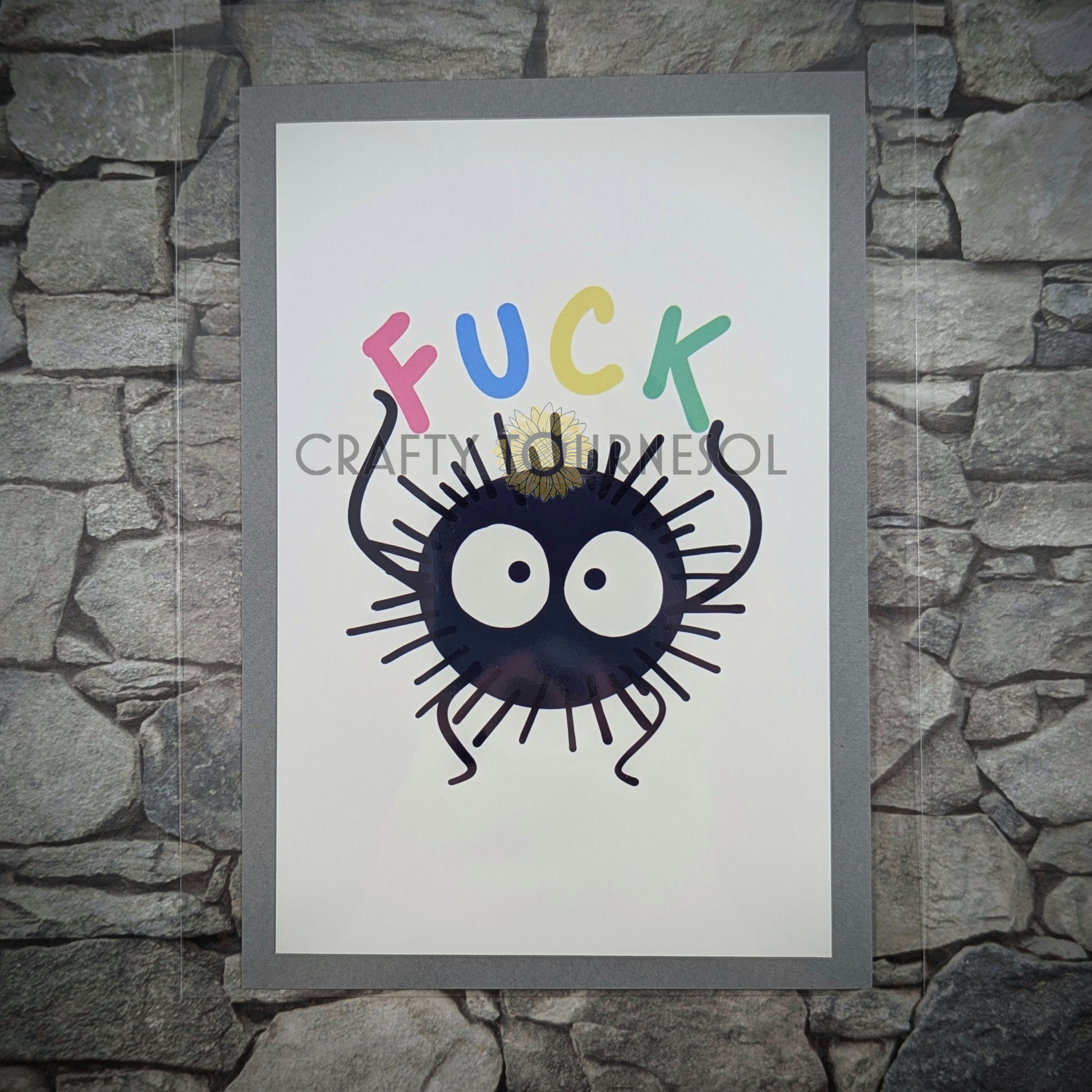 "4"x6" fanart print of soot sprite, holding 'Fuck' text in playful colors. Perfect for anime fans and mental health advocates adding a playful, geeky touch to favorite space."