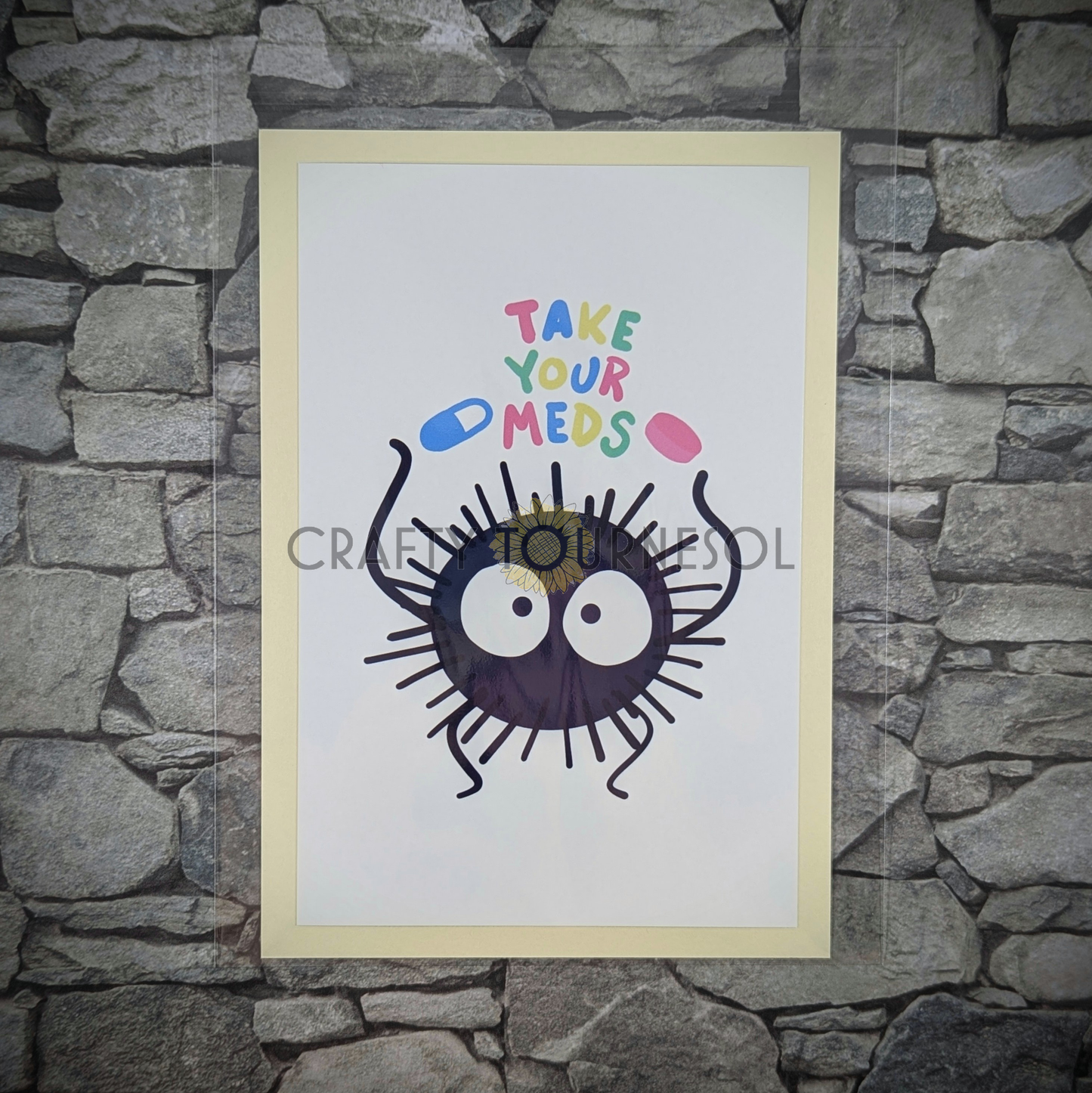 "4"x6" fanart print of soot sprite, holding 'Take Your Meds' text in playful colors. Perfect for anime fans and mental health advocates adding a playful, geeky touch to favorite space."