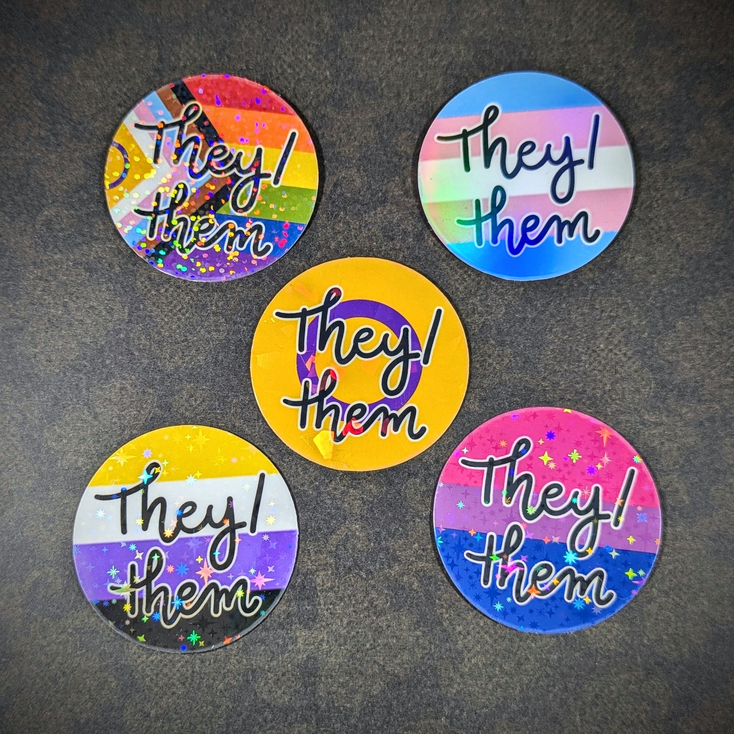 "Round holographic pronoun stickers featuring 'They them' in various LGBTQ+ pride flag designs, perfect for expressing gender identity and inclusivity on laptops, water bottles, and notebooks."