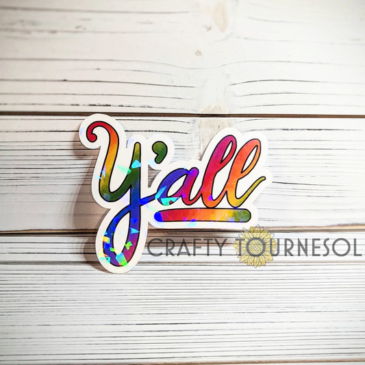 "Colorful rainbow 'Y'all' sticker with holographic shine, featuring a vibrant design perfect for adding Midwestern, Southern charm and LGBTQ+ pride to laptops, notebooks, and personal items."