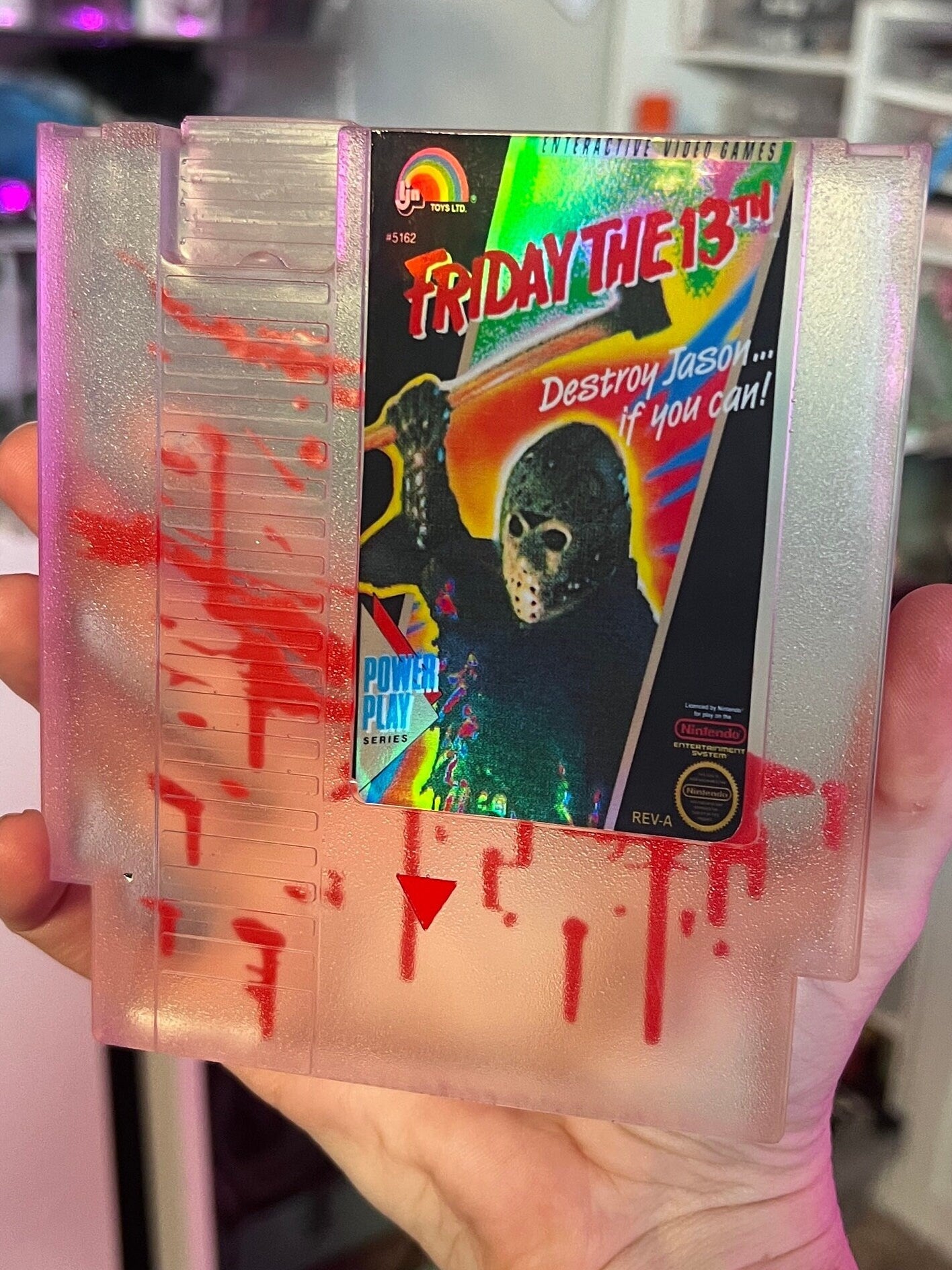 Friday the 13th NES cartridge-inspired collectible with blood splatter design featuring Jason Voorhees. Perfect for retro horror fans and gaming enthusiasts who love unique, creepy decor.