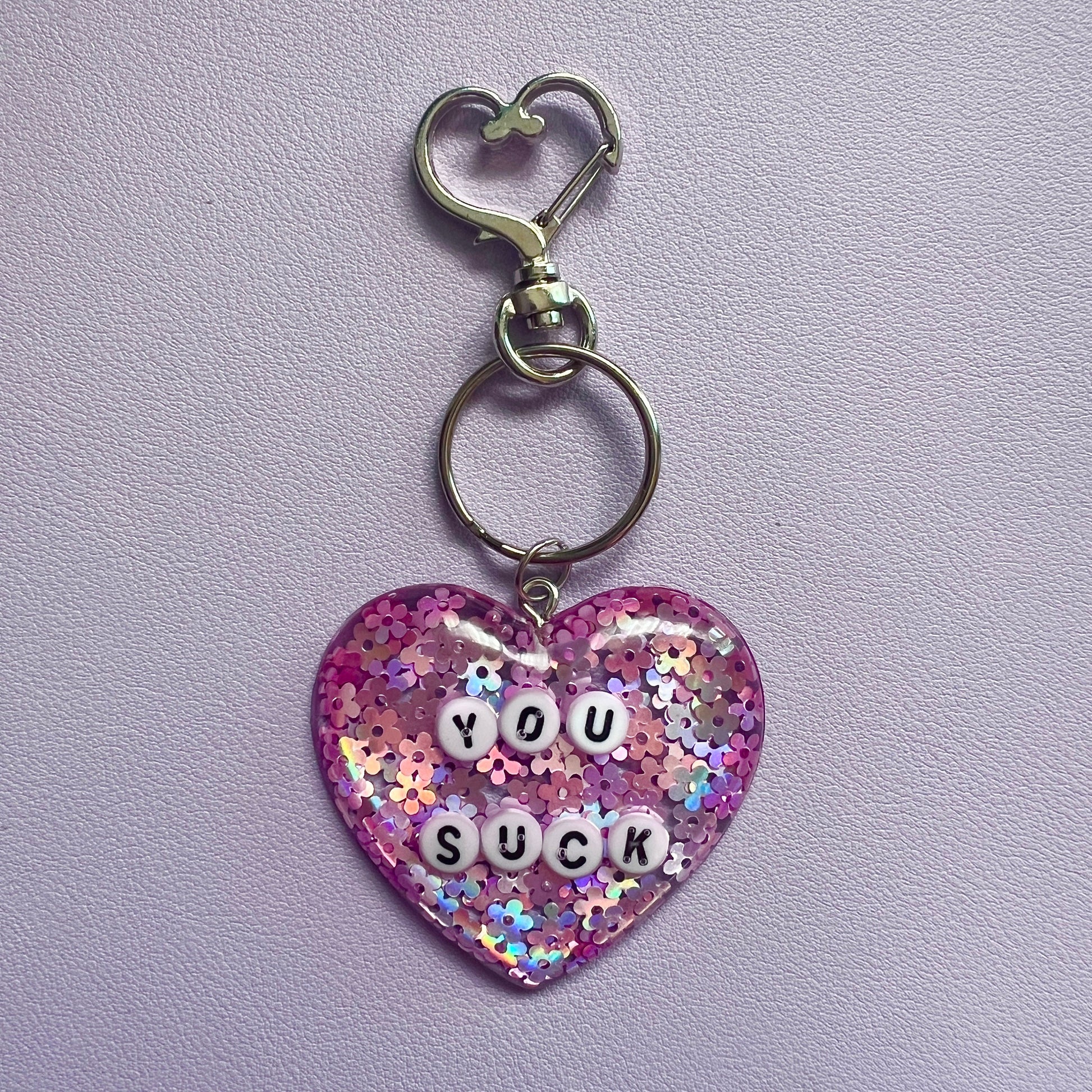 Customizable resin heart keychain with funny phrases. A fun, quirky gift for friends, this keychain can be personalized from a list of fun phrases. Perfect for adding personality to your keys or bags.