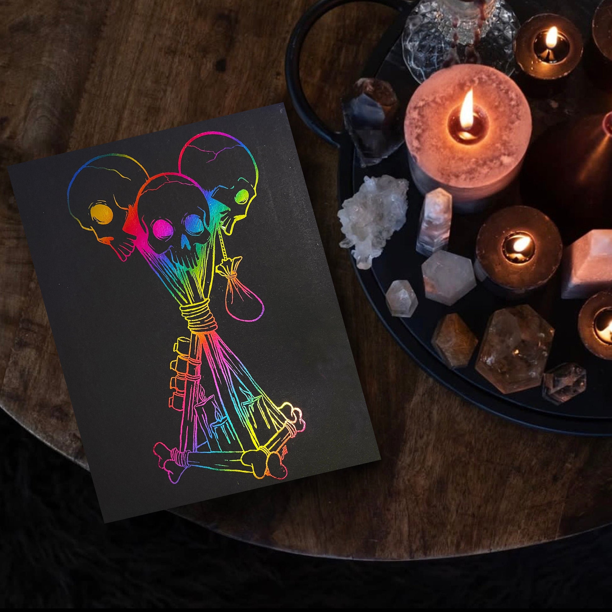 Hand-foiled Dead by Daylight totem artwork featuring three rainbow-colored skulls tied with candles and bones on black cardstock. This custom, vibrant totem design brings a unique twist to iconic game imagery, perfect for horror and gaming fans.