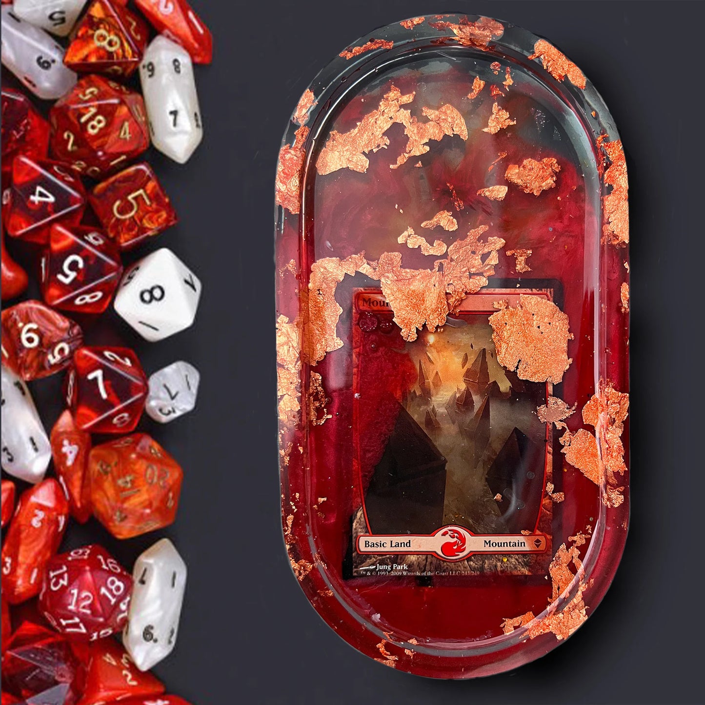 Handmade resin trinket tray featuring a Magic the Gathering Mountain land design with red tones + rose gold foil accents. Perfect for dice, cards, or small items, ideal for gamers and collectors. Unique addition to any Magic the Gathering collection.