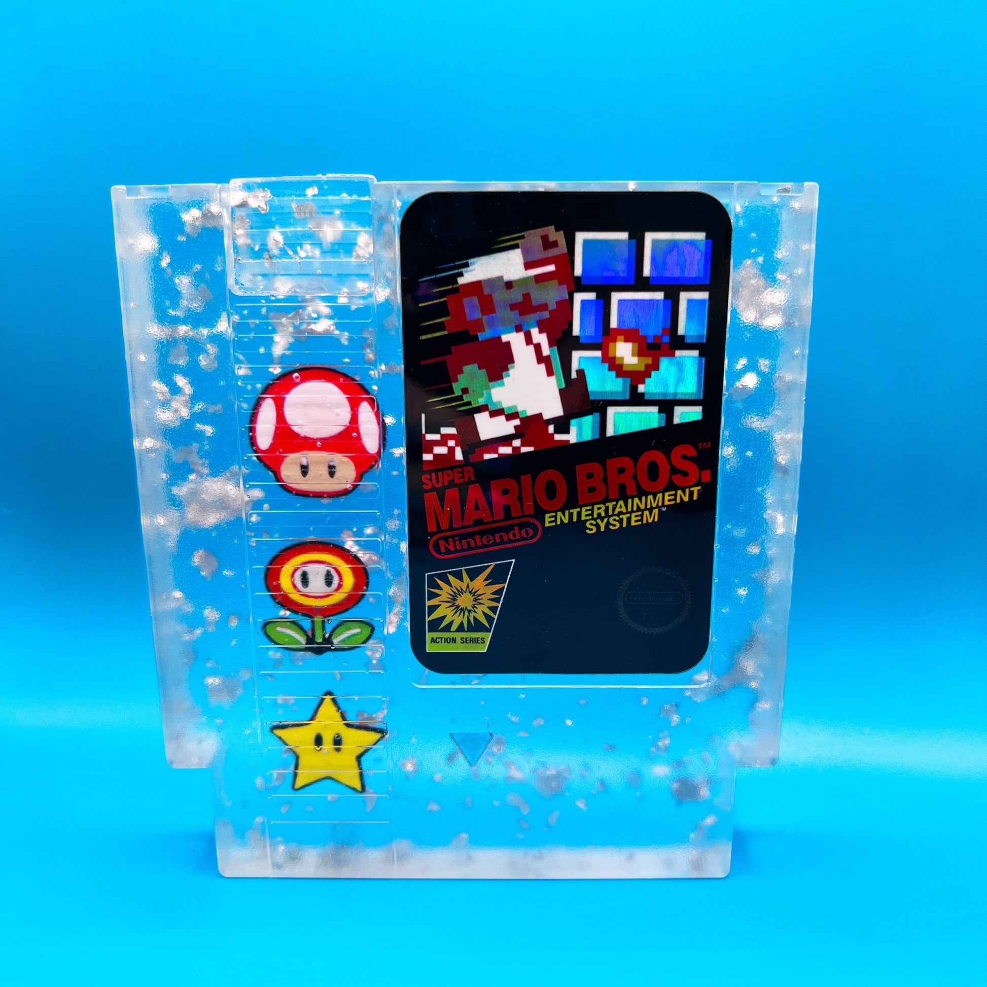 Handmade resin art featuring a retro Super Mario Bros NES cartridge with classic icons like the mushroom, fire flower, and star. Perfect for gamers, collectors, or unique home decor to add a nostalgic touch to any space.