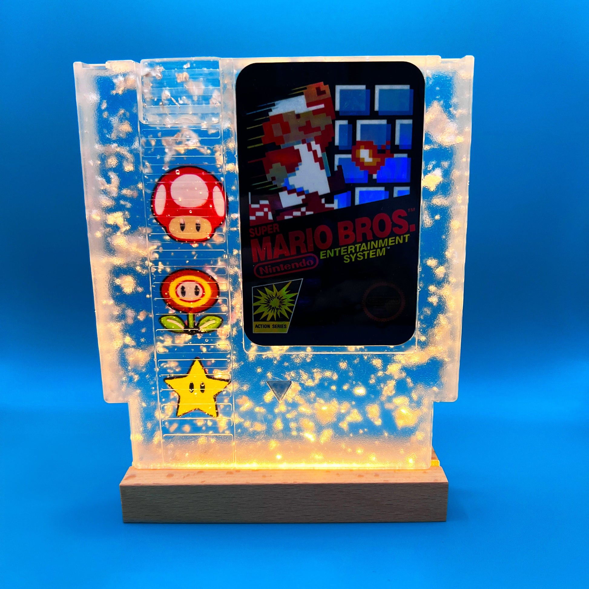 Handmade resin art featuring a retro Super Mario Bros NES cartridge with classic icons like the mushroom, fire flower, and star. Perfect for gamers, collectors, or unique home decor to add a nostalgic touch to any space.