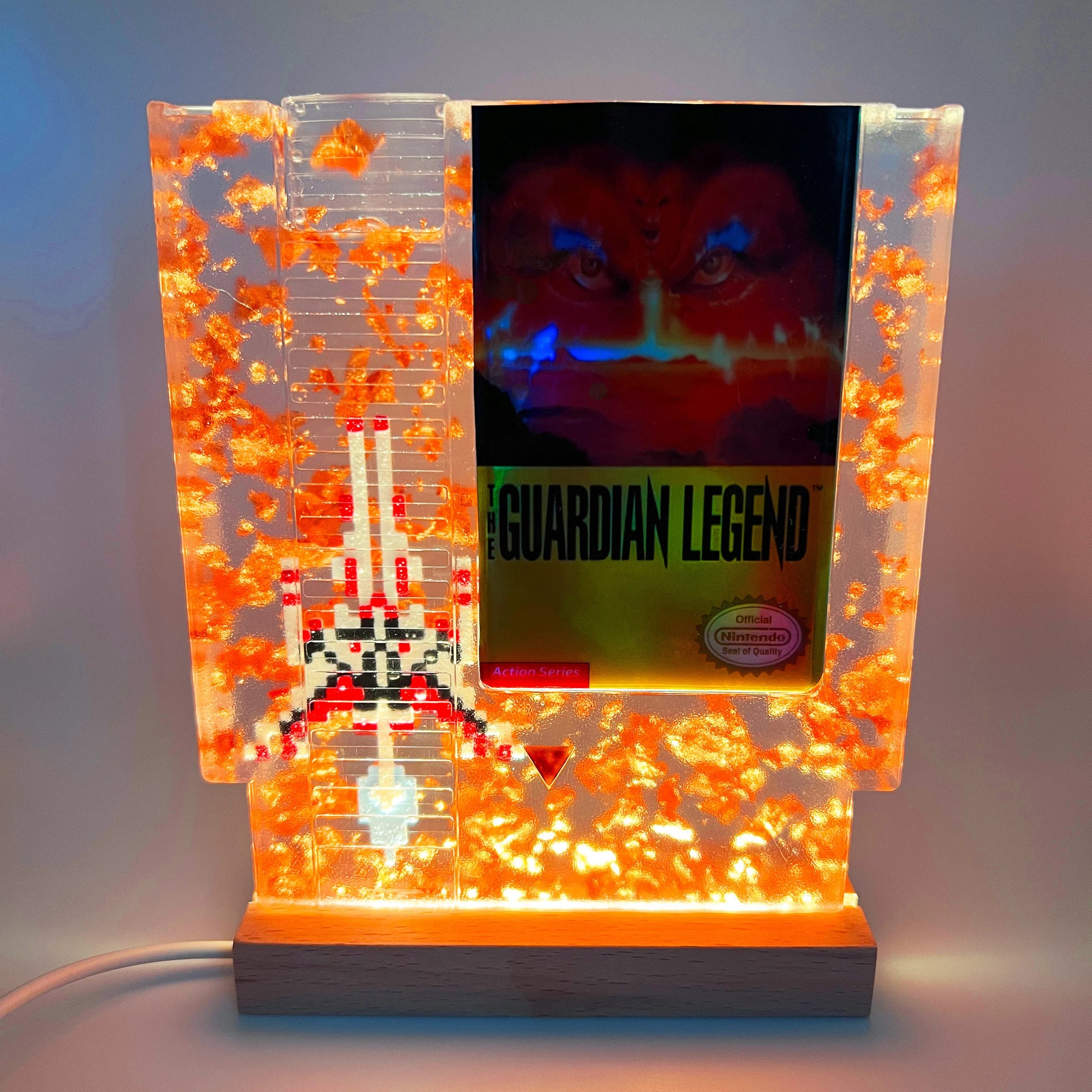 Handcrafted The Guardian Legend custom NES cartridge featuring vibrant orange and holographic elements. This retro gaming art piece adds a unique flair to any collection.