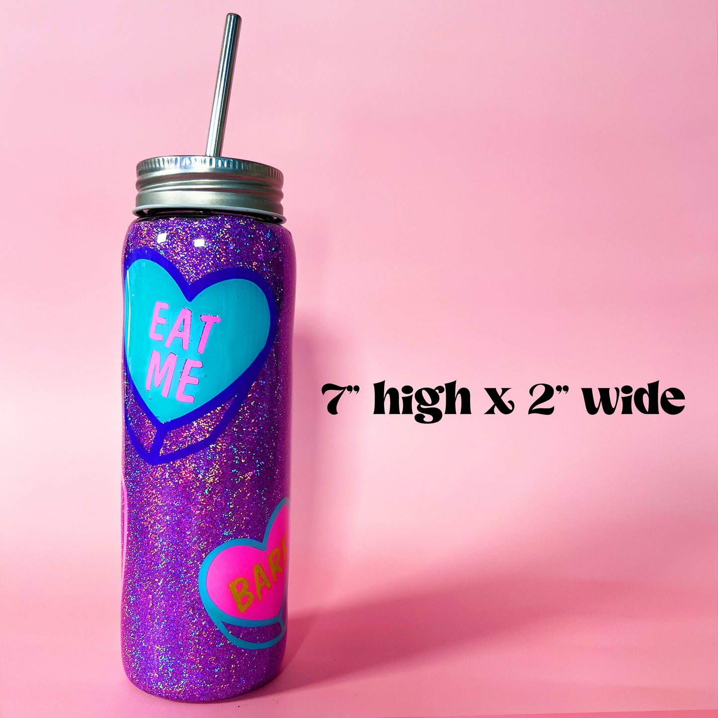 Handmade glitter tumbler with funny candy heart design in vibrant pink, blue, and purple colors. The tumbler features a shiny, sparkly finish and comes with a reusable metal straw. Perfect for adding a fun, quirky touch to your drinkware collection.