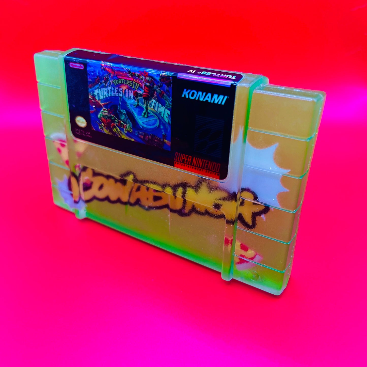 Handmade resin replica of the classic SNES game Turtles in Time. Vibrant green design with graffiti-style elements and retro cartridge art. Perfect for gamers, collectors, or as a unique shelf display for TMNT fans