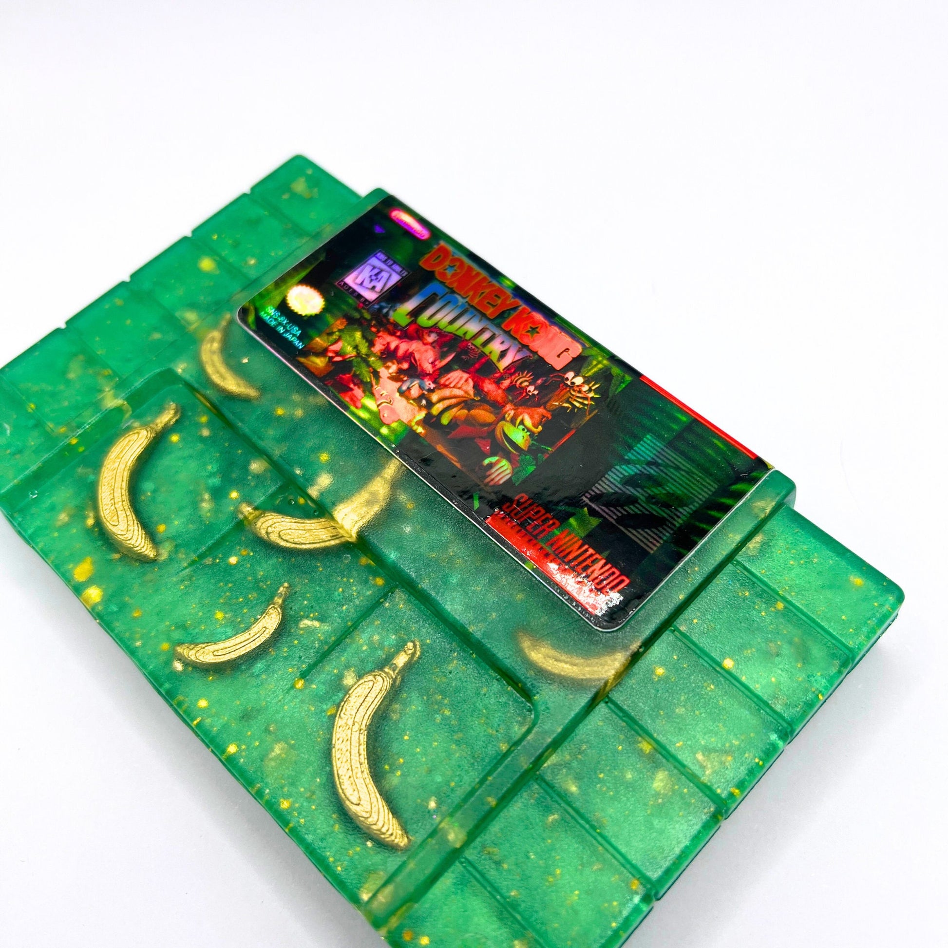 Retro Donkey Kong Country SNES cartridge art featuring embedded golden banana accents. Handmade and perfect for collectors or retro gaming fans seeking unique decor or gifts.