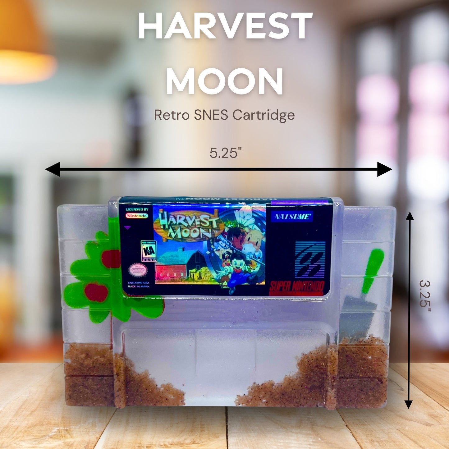 Custom resin art featuring a clear Super Nintendo game cartridge of Harvest Moon filled with decorative sand and tiny plant accents. Perfect as a nostalgic, geek-inspired desk or shelf display for retro gaming enthusiasts.