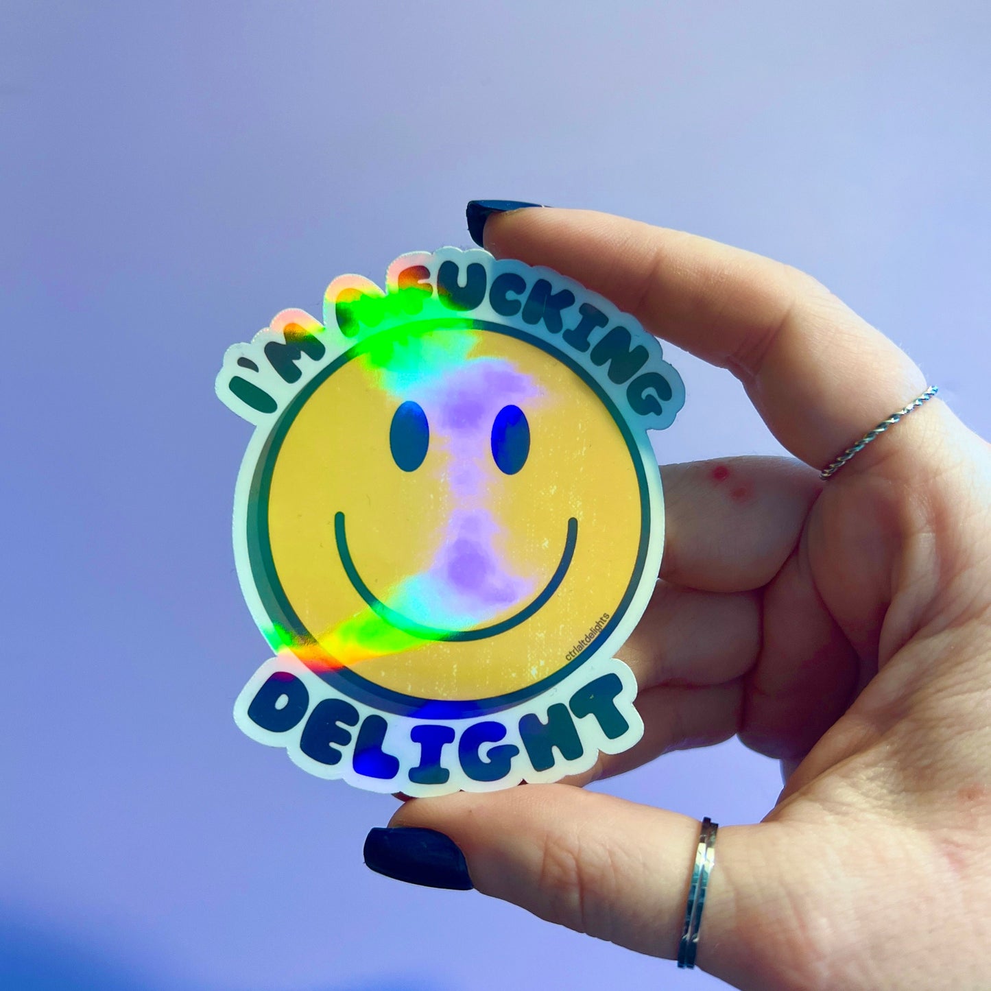 A holographic sticker featuring a smiley face with the bold text I'm a F**king Delight. Perfect for adding humor and positivity to your belongings.