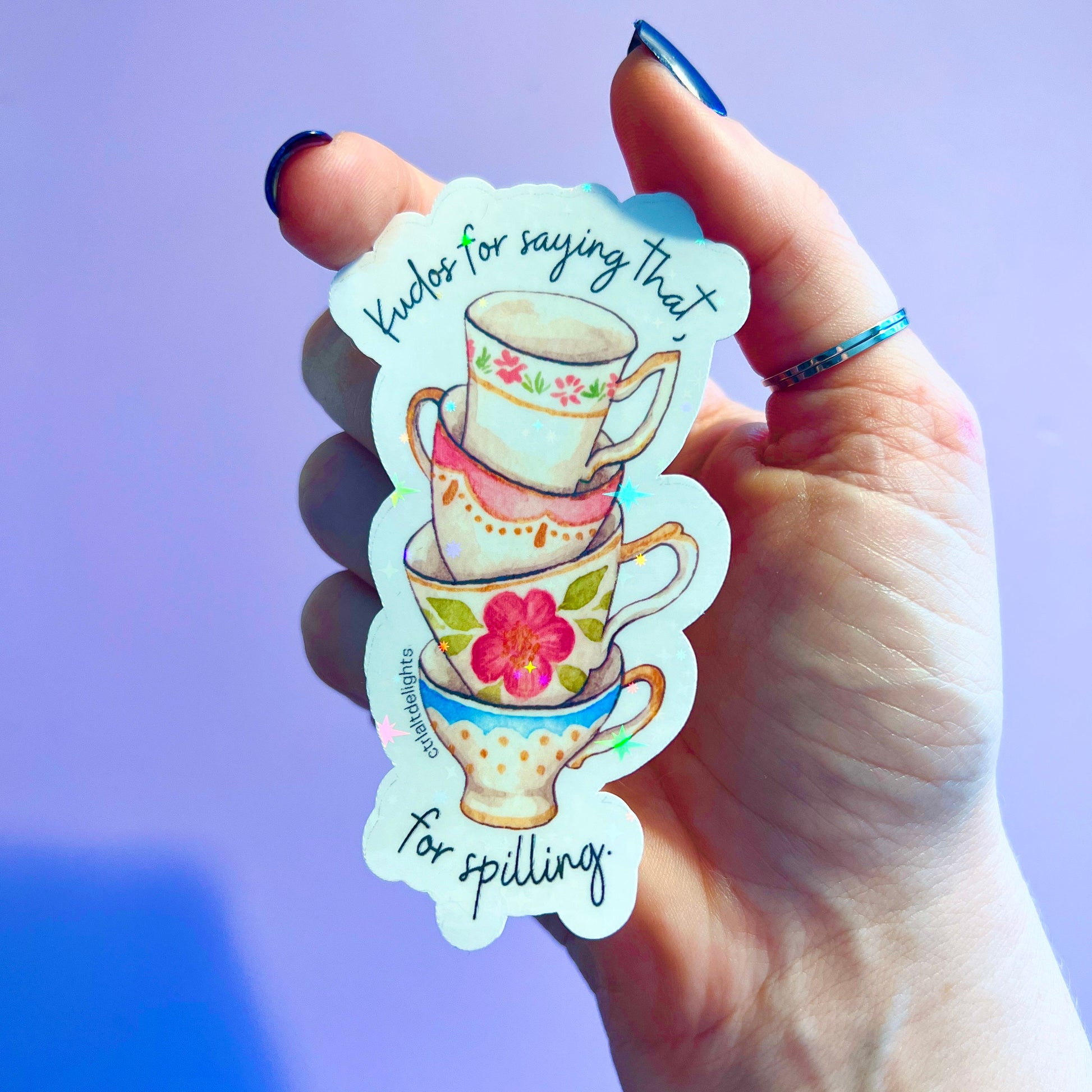 Whimsical vinyl sticker featuring a stack of colorful tea cups with the phrase Kudos for saying that. Perfect for tea lovers and those who enjoy spilling the tea. Great for decorating laptops or journals