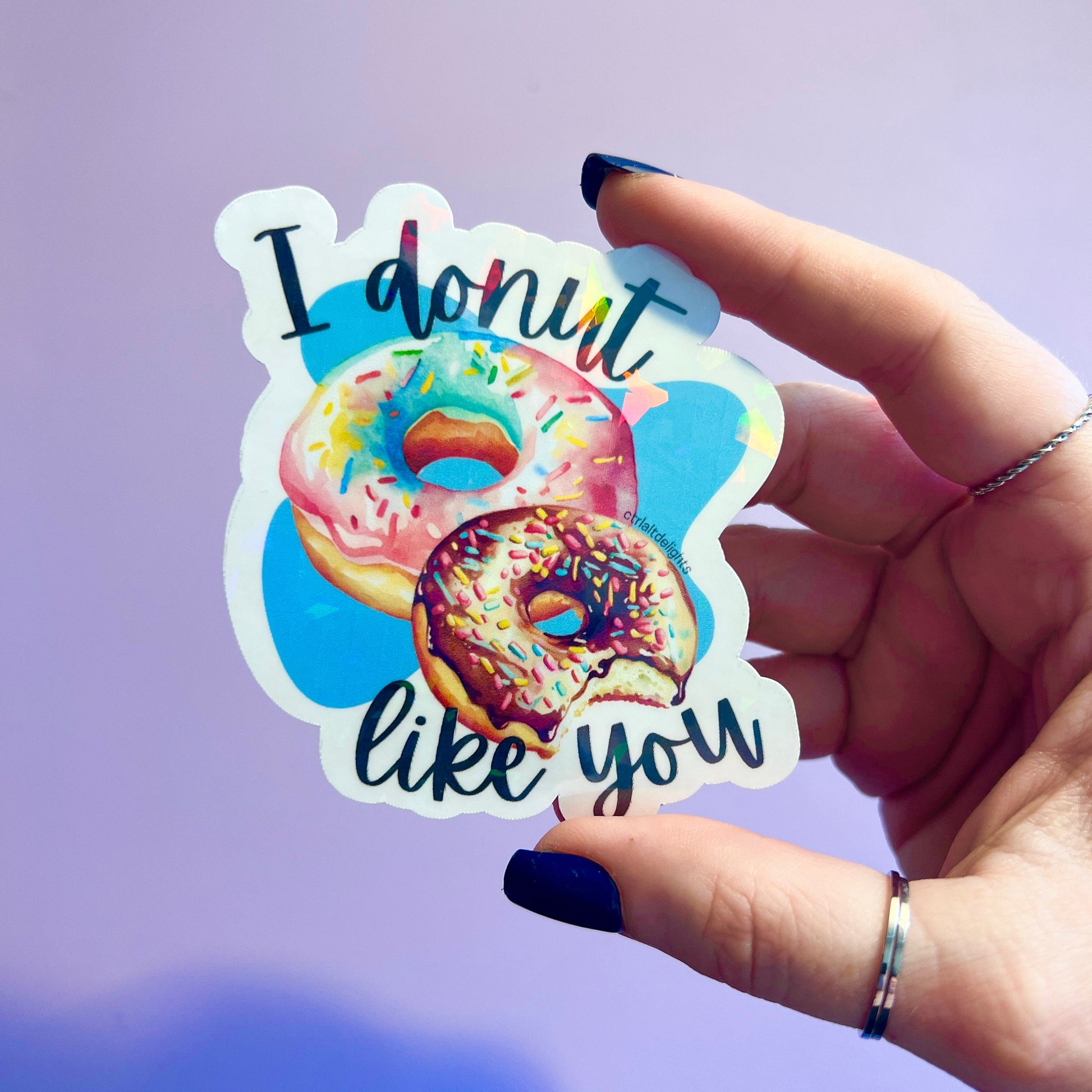 This adorable holographic donut sticker features two colorful donuts and the pun I Donut Like You. Perfect for laptops, water bottles, or journals, it makes a great gift for food lovers and pun enthusiasts.