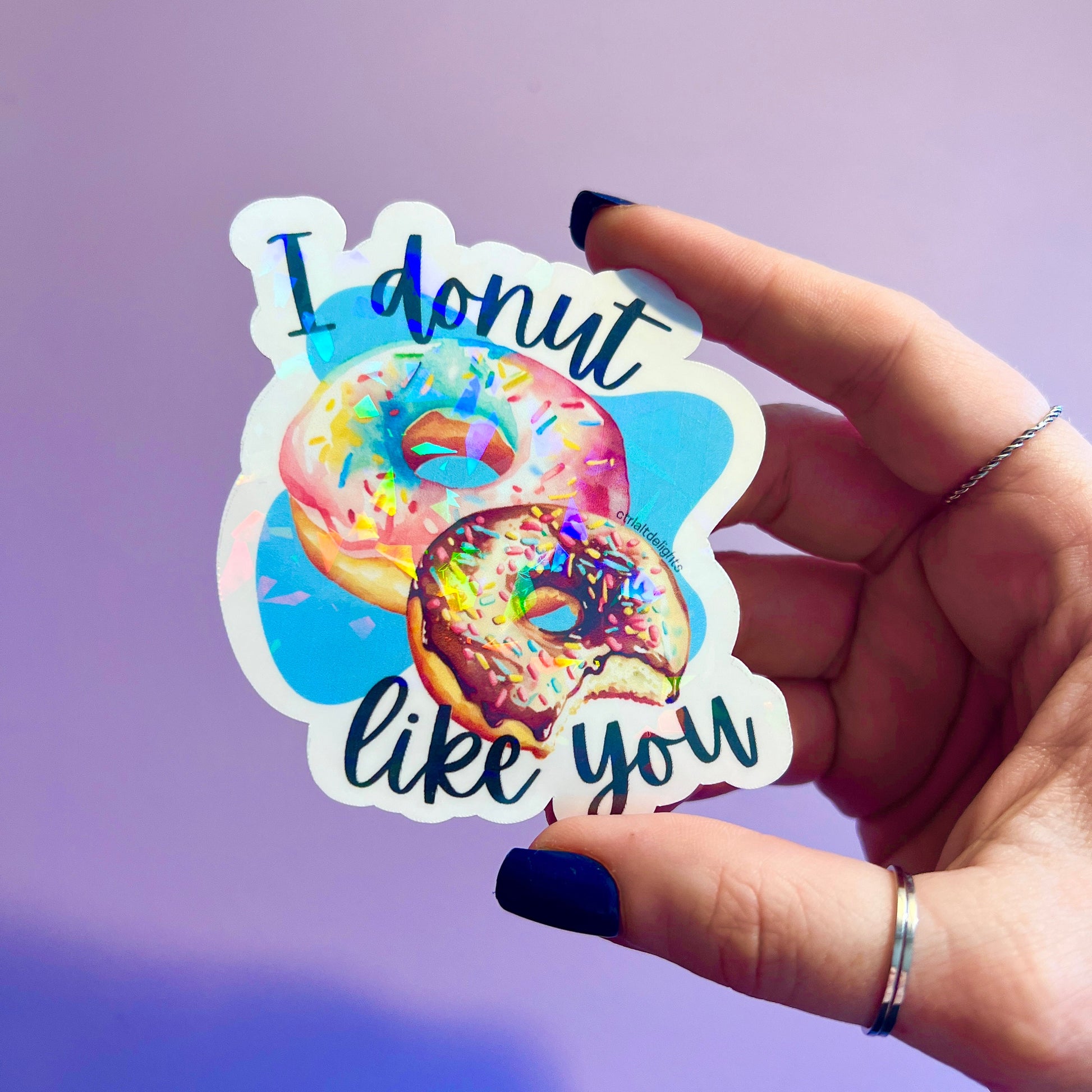 This adorable holographic donut sticker features two colorful donuts and the pun I Donut Like You. Perfect for laptops, water bottles, or journals, it makes a great gift for food lovers and pun enthusiasts.